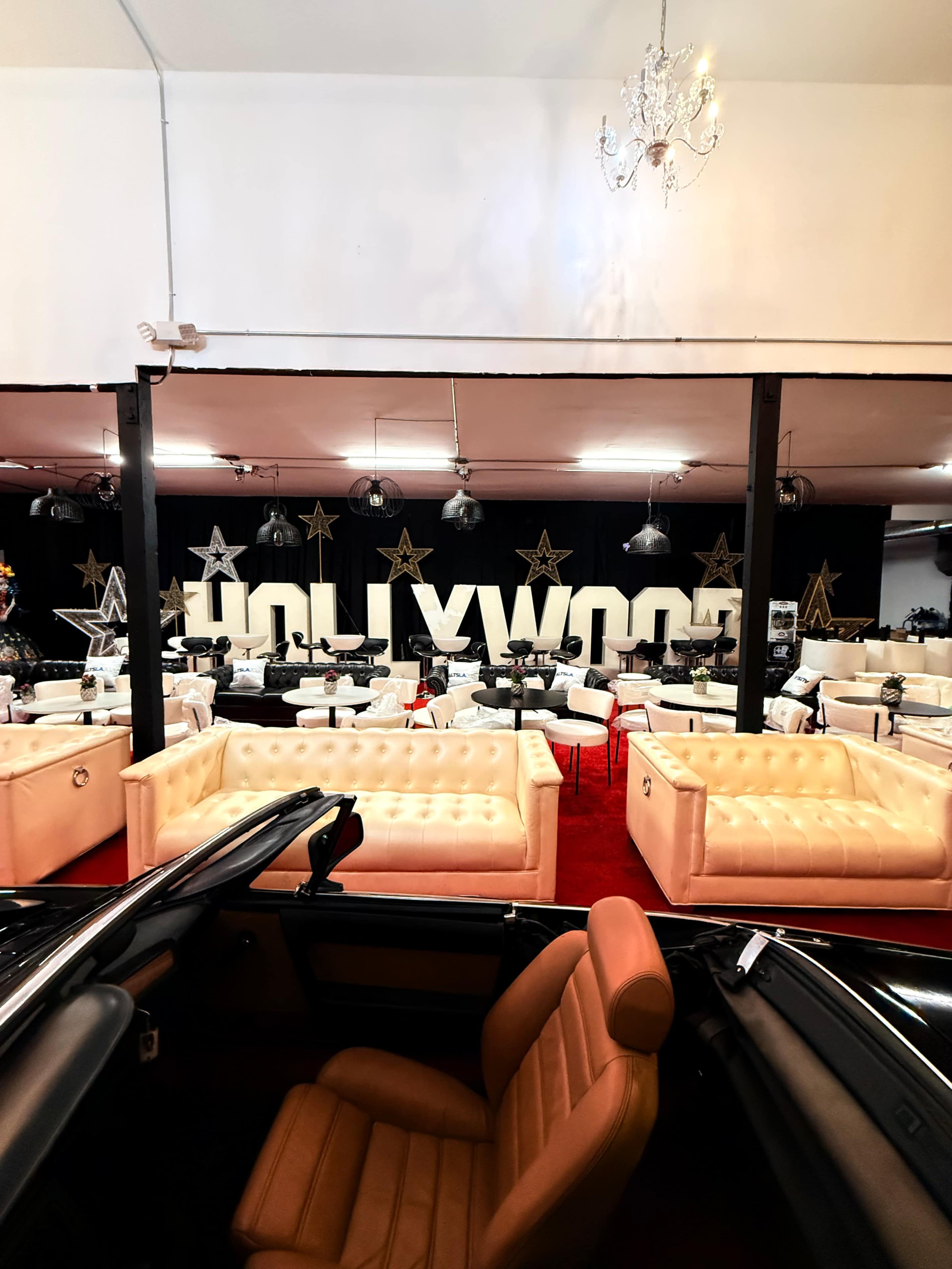 The image shows an interior space with a large "HOLLYWOOD" sign, white sofas, and decorative furniture.