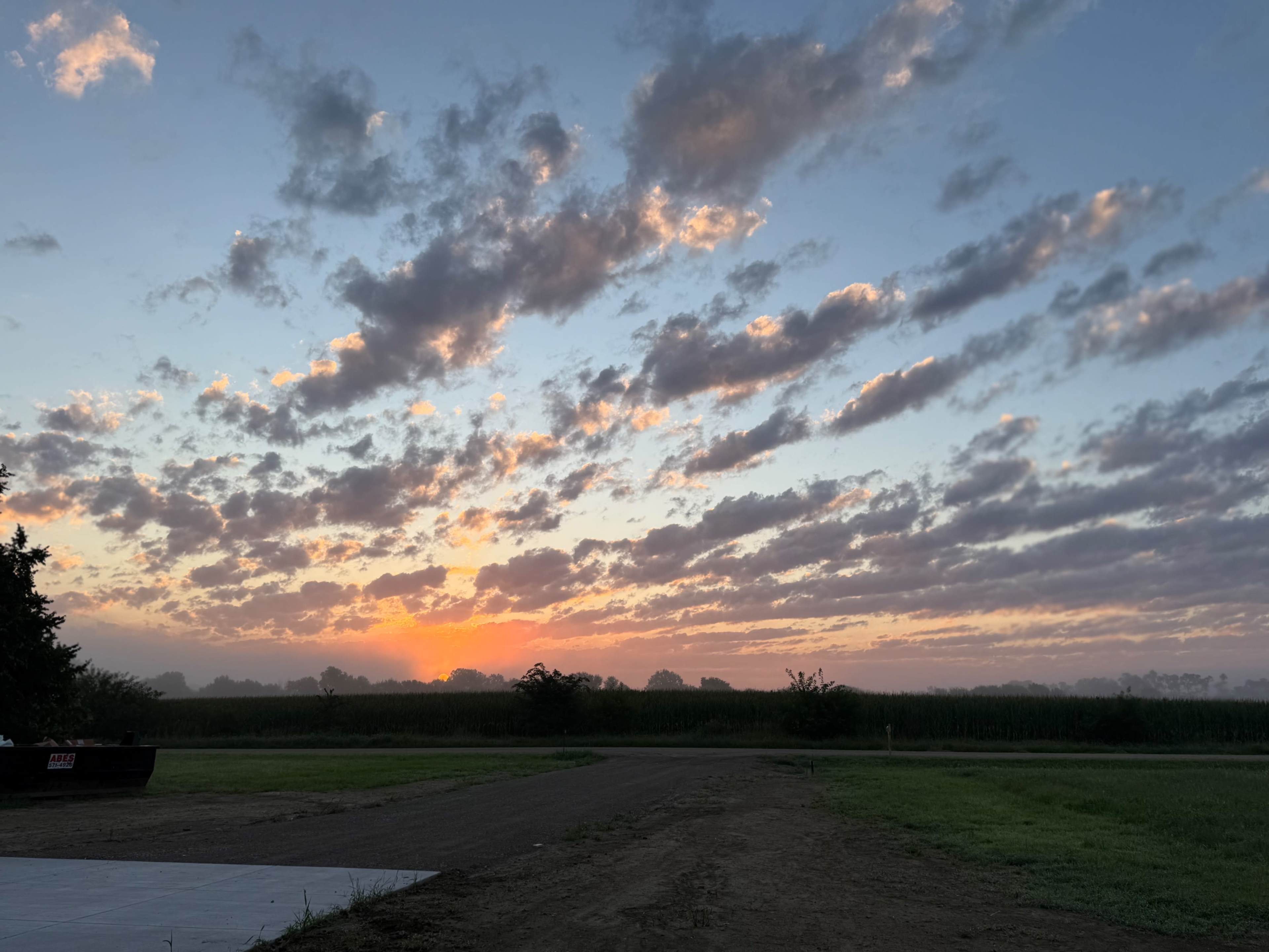The image shows a sunrise with colorful clouds over a wide, open landscape.