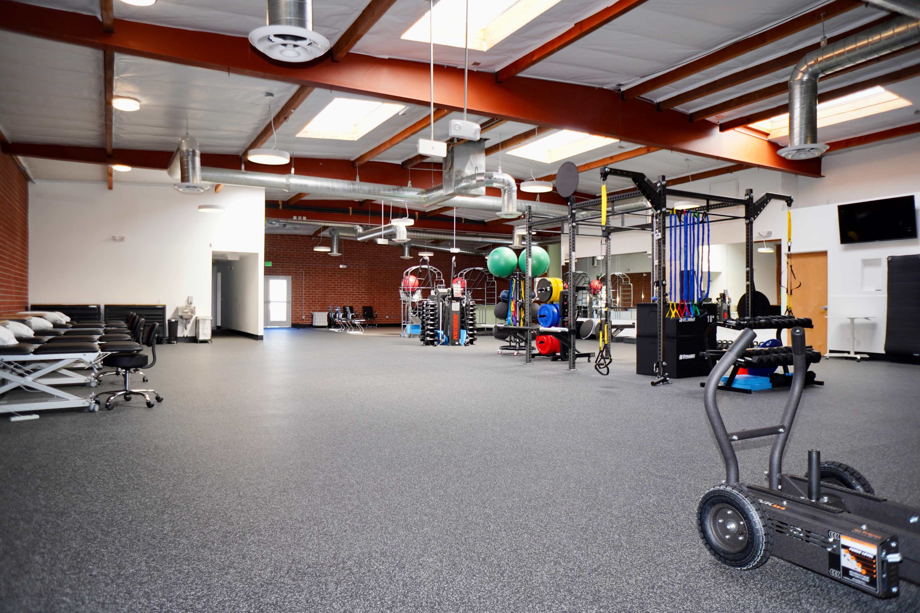 A spacious gym interior equipped with various fitness machines, weights, and training equipment.