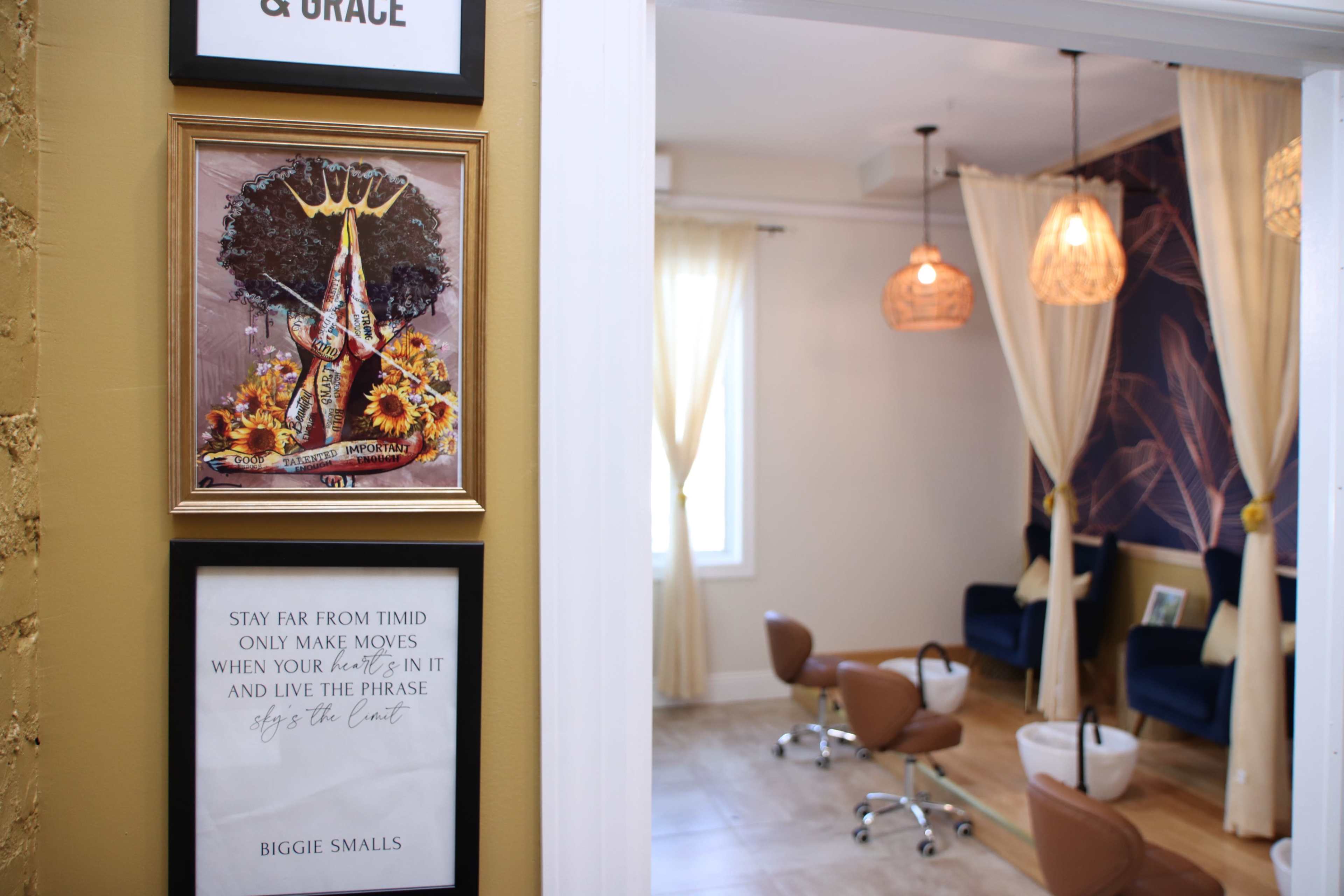A wall with framed artwork and a quote, leading into a room with seating and decorative lighting.