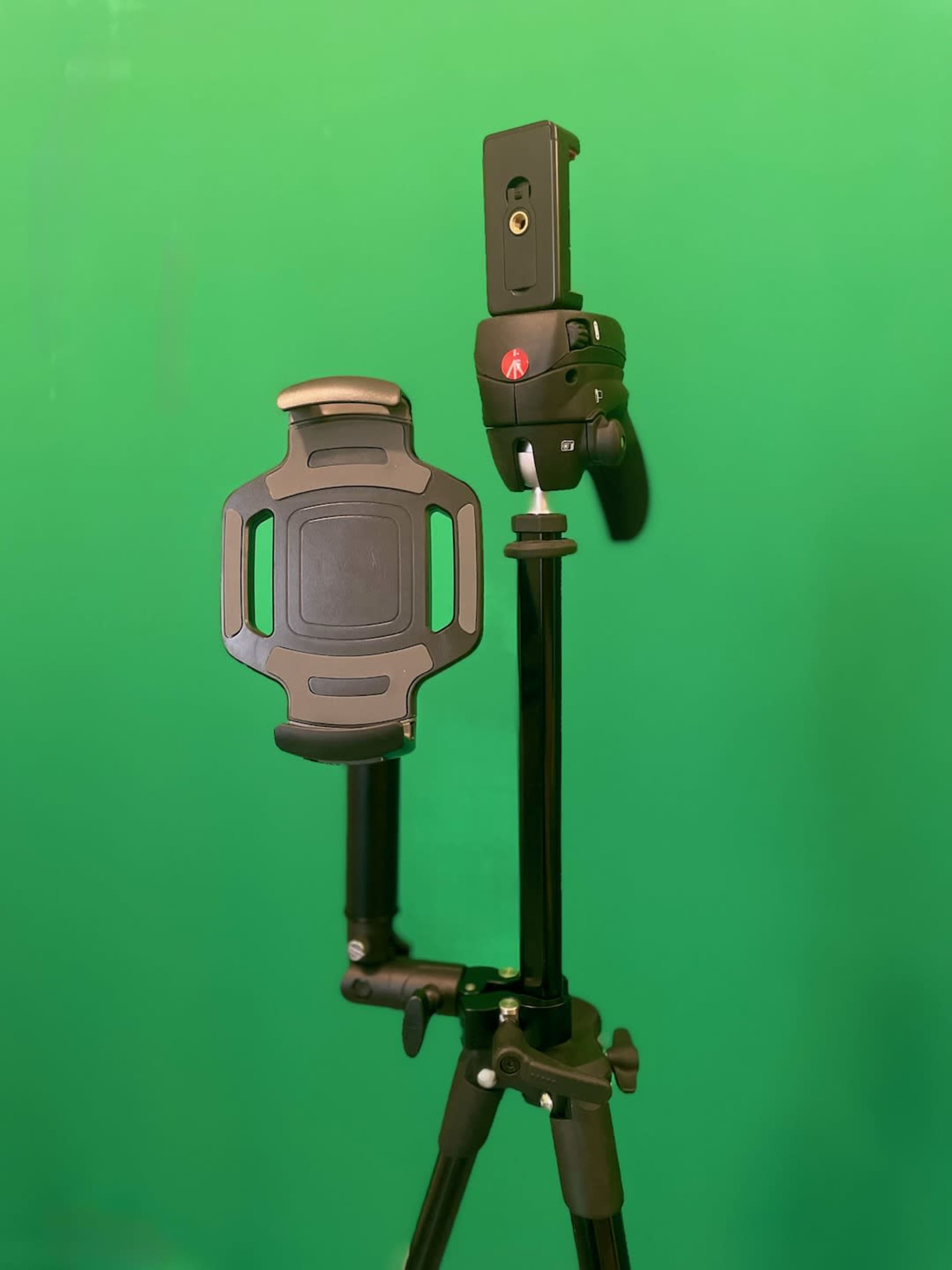 The image displays a black tripod with a mobile phone holder attached, set against a green backdrop.