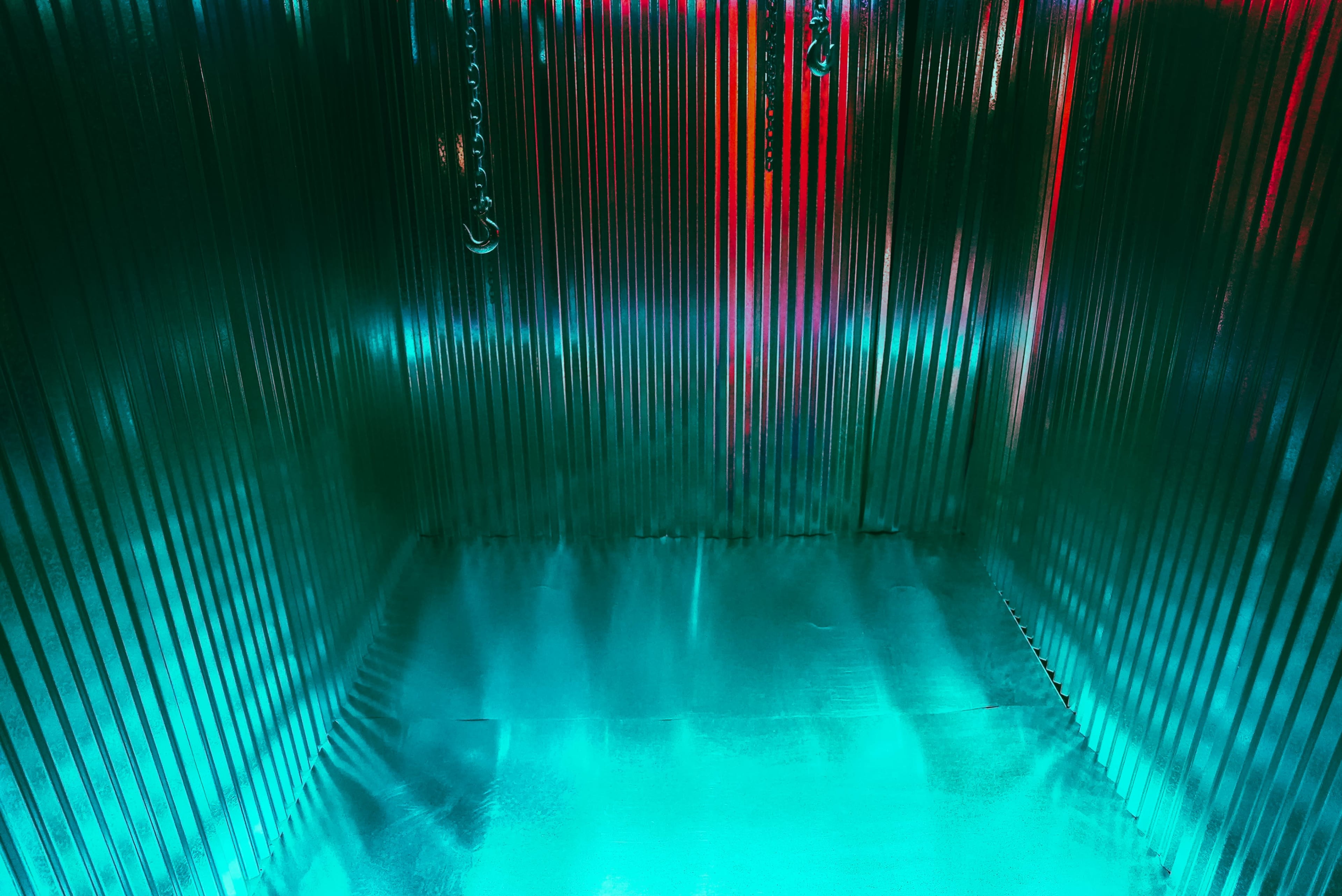 A shiny, metallic interior with vertical stripes and a reflective surface, illuminated by green and red light.