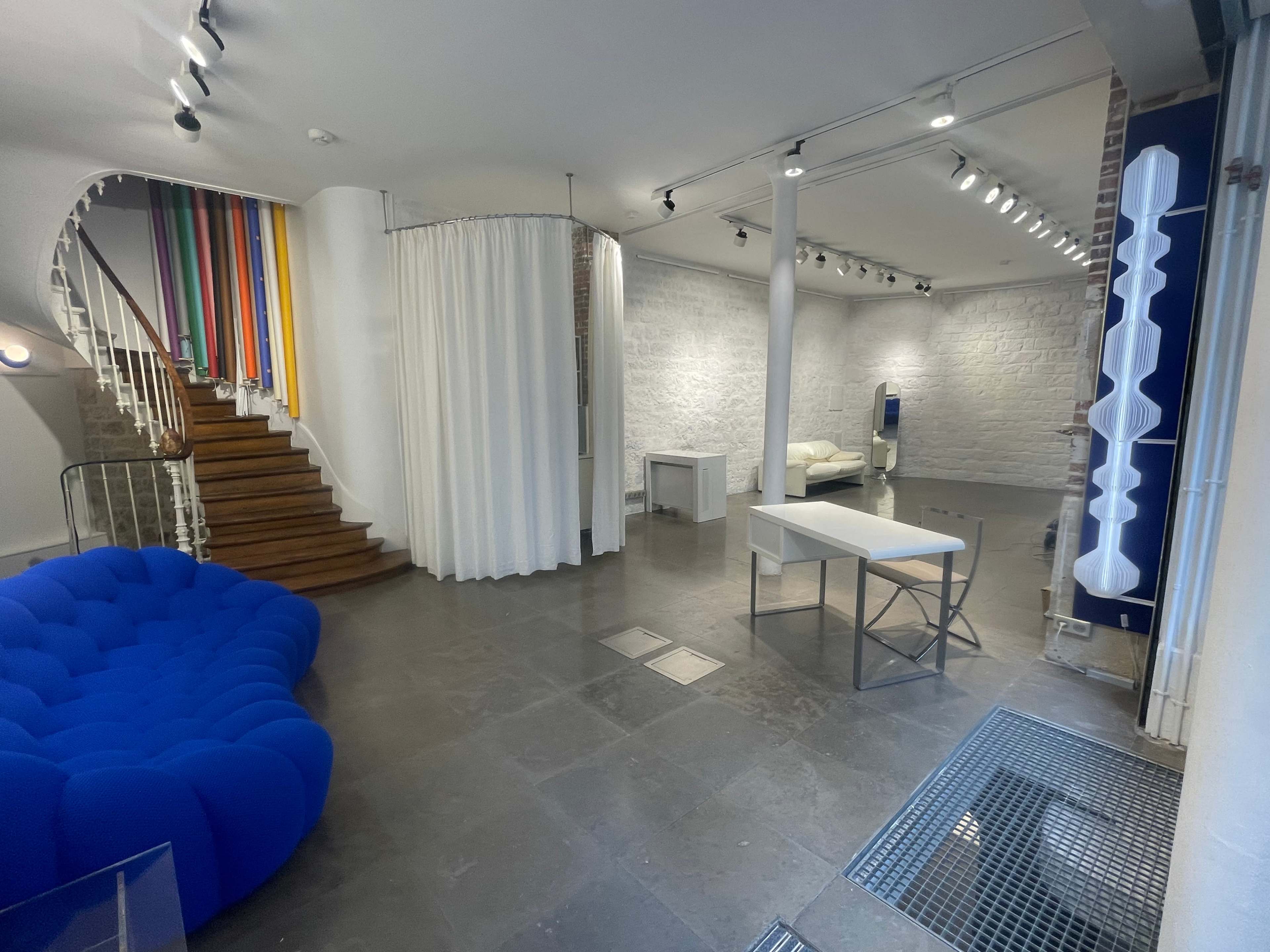A spacious room with a blue couch, a white table, and colorful dividers leading up a staircase.