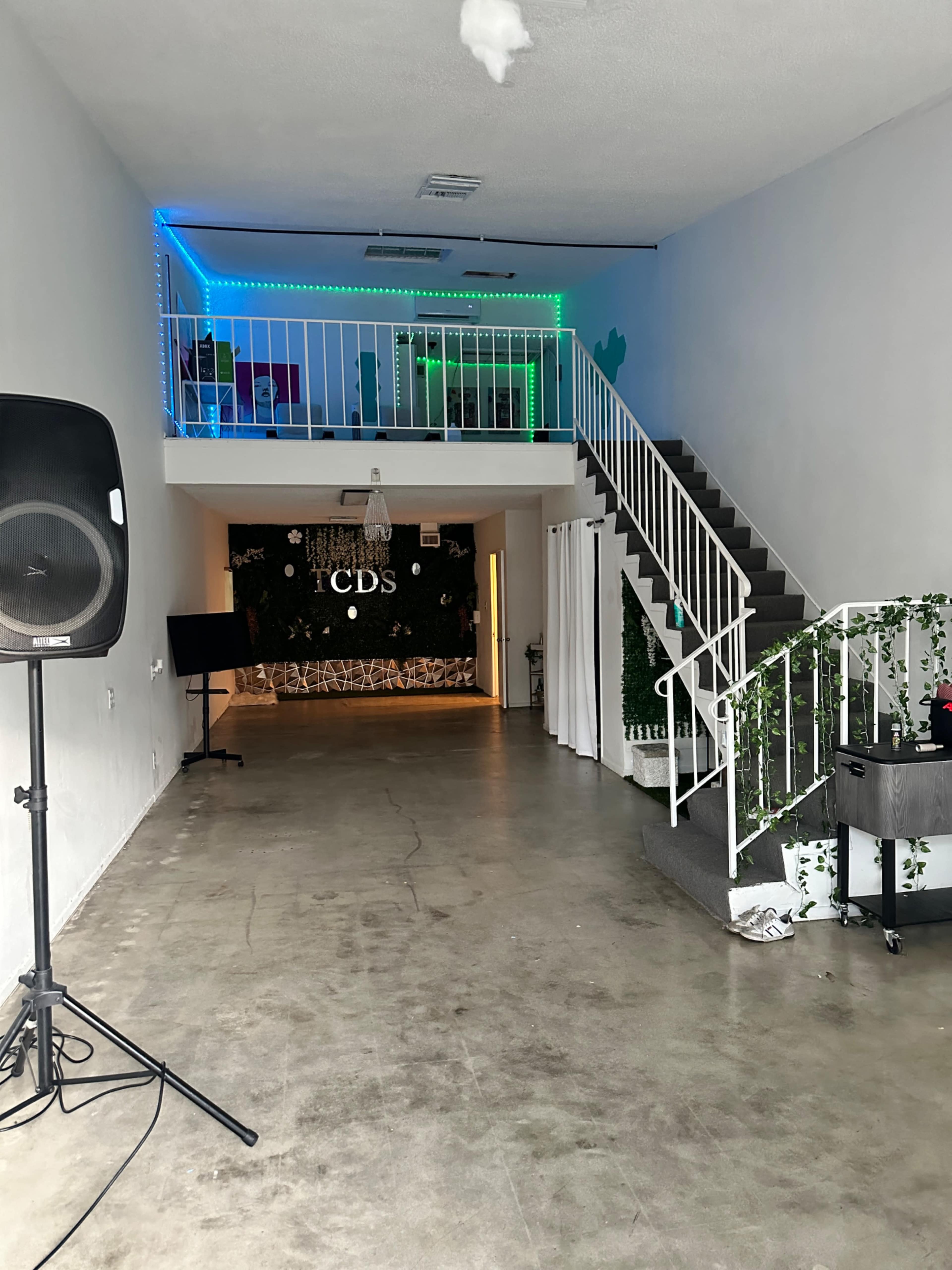 An interior space featuring a staircase, green and blue LED lights, and a wall adorned with greenery.
