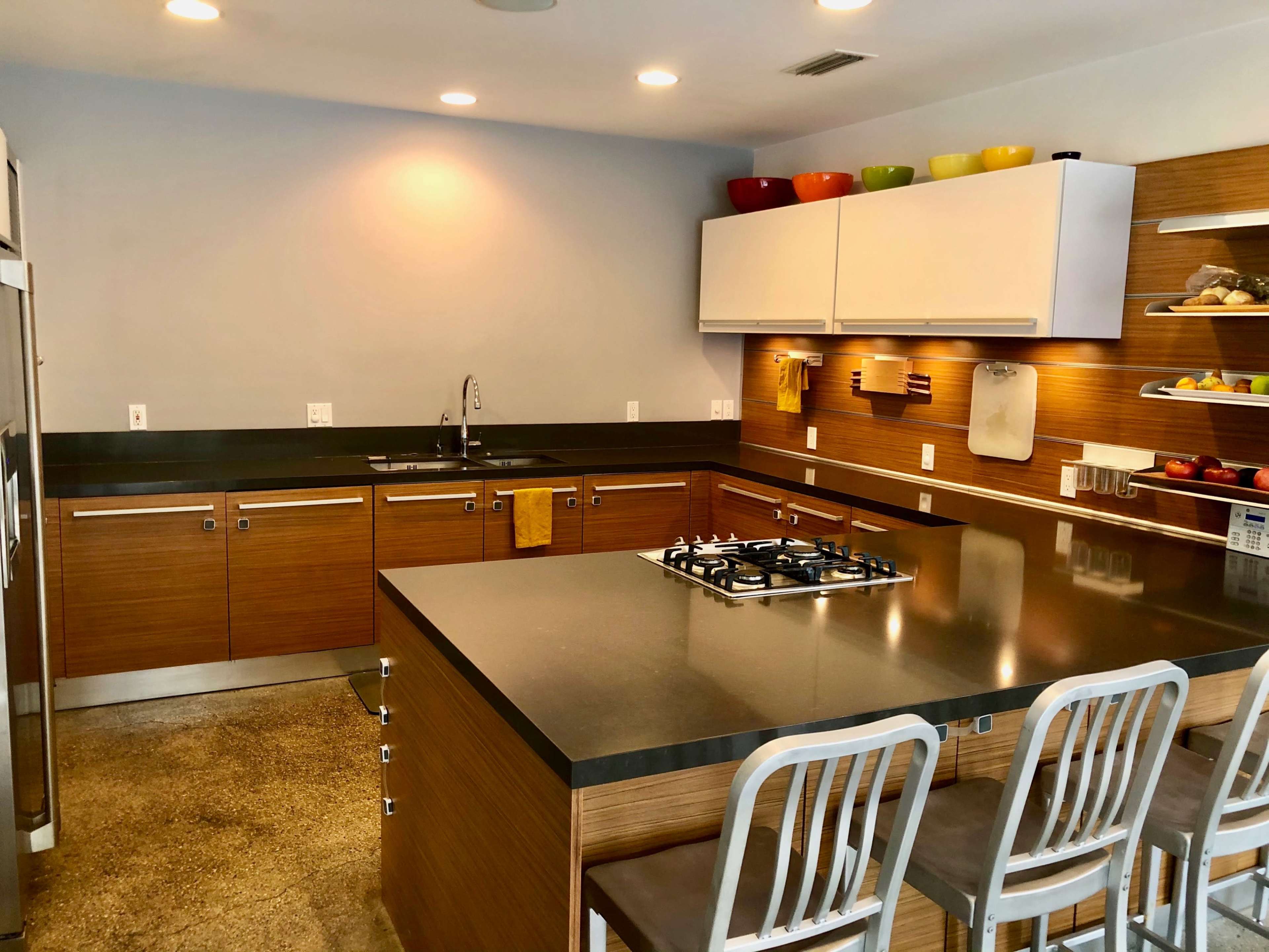 The kitchen features wooden cabinetry, a central island with a gas cooktop, and modern appliances against a neutral backdrop.