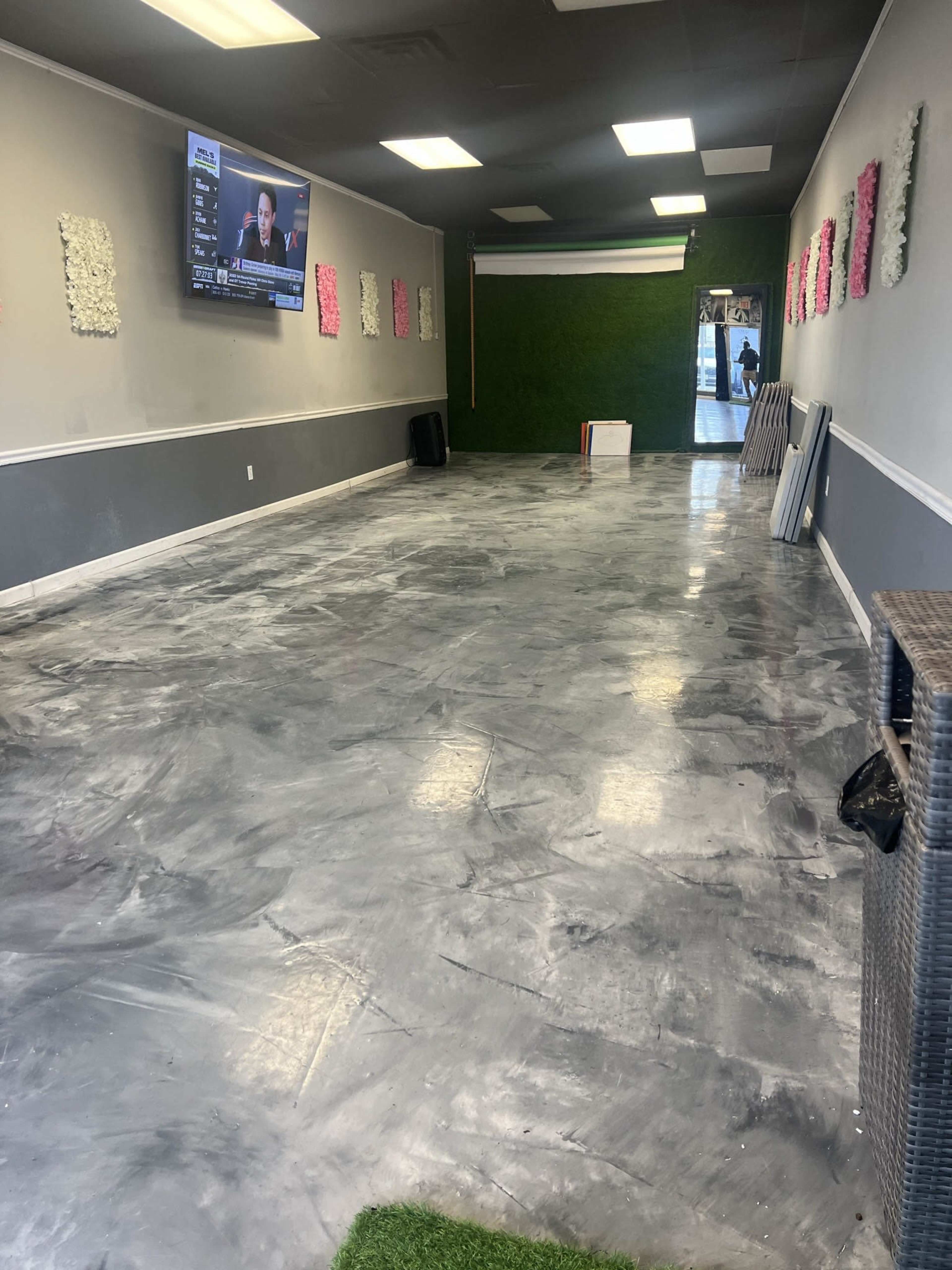An empty room with a polished concrete floor, decorated with wall panels and a television mounted on one wall.