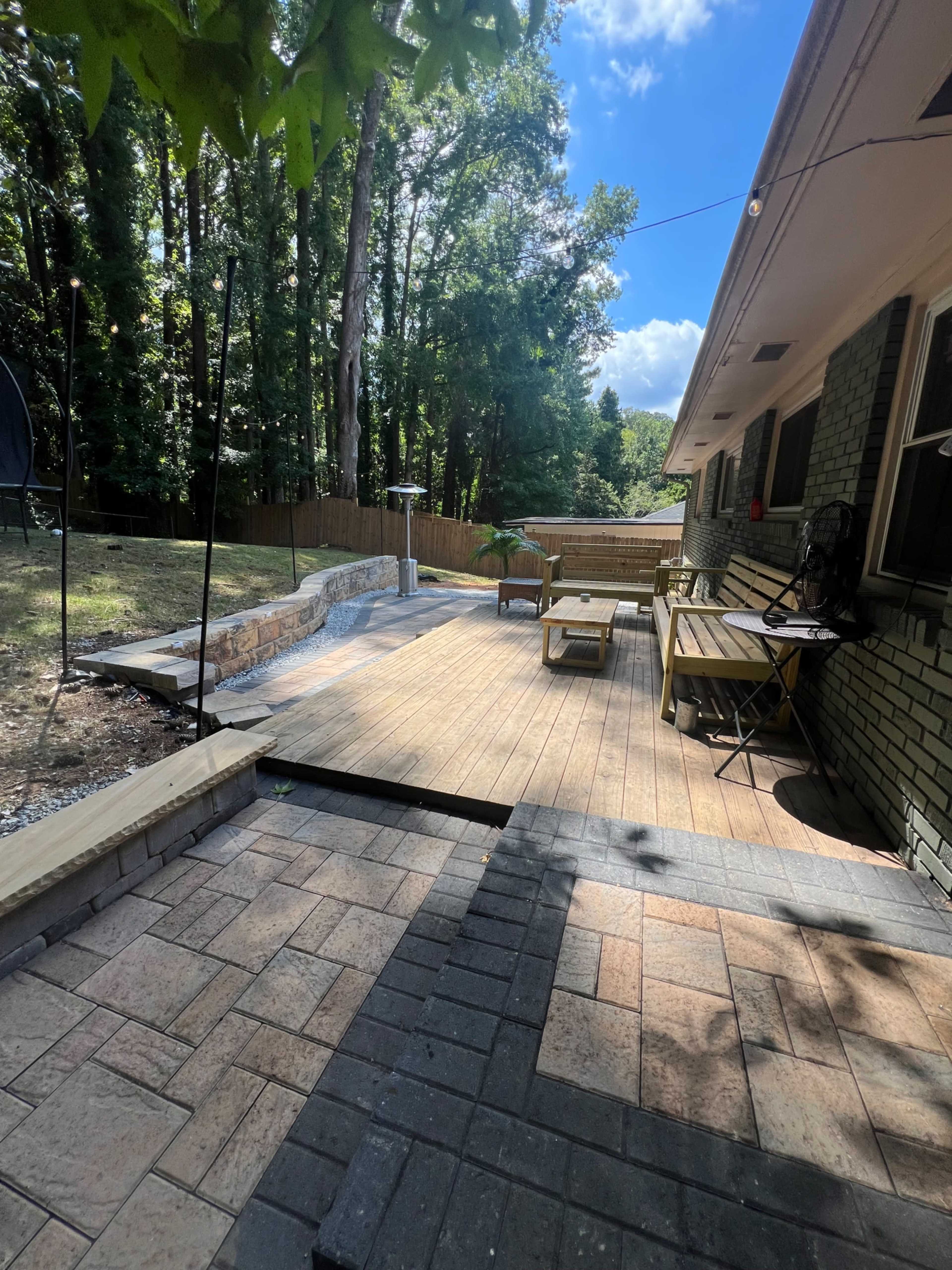 The image shows a wooden deck area with patio furniture, surrounded by trees and a fenced yard.