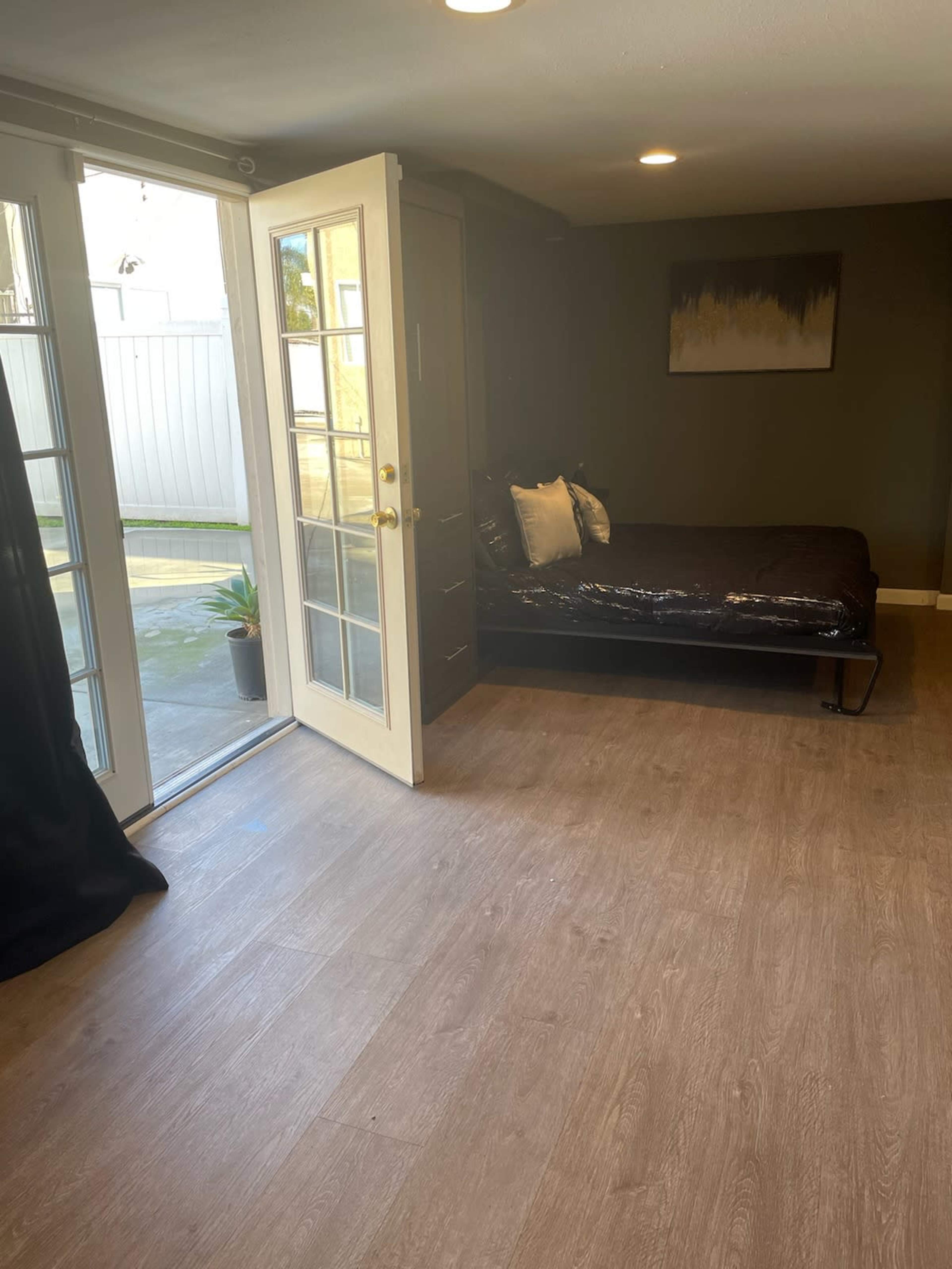 The image shows a small room with a daybed and a set of French doors leading to an outdoor area.