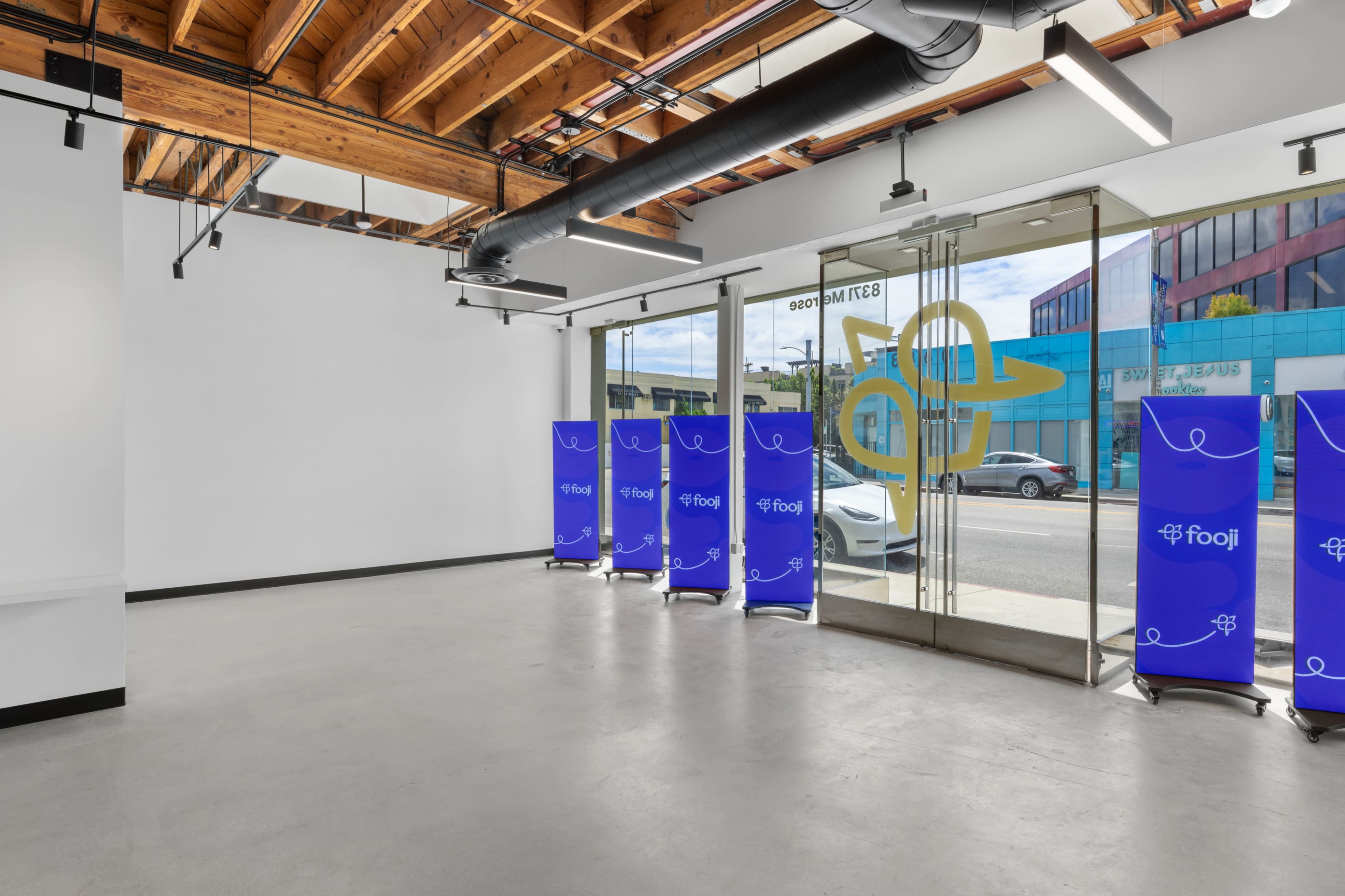 A modern, empty retail space with large glass doors and blue promotional banners inside.