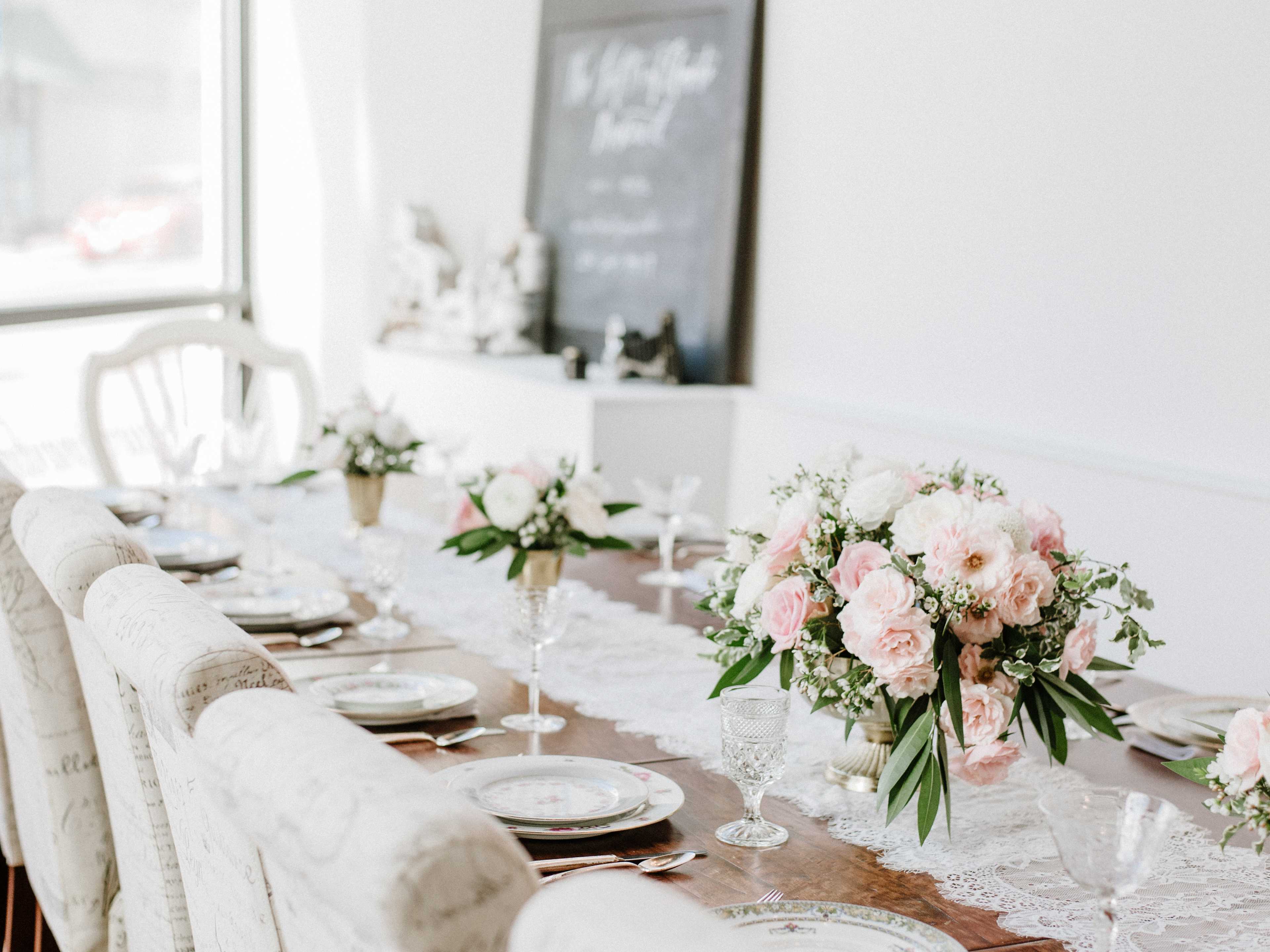 A long dining table is elegantly set with floral centerpieces, fine china, and crystal glassware.