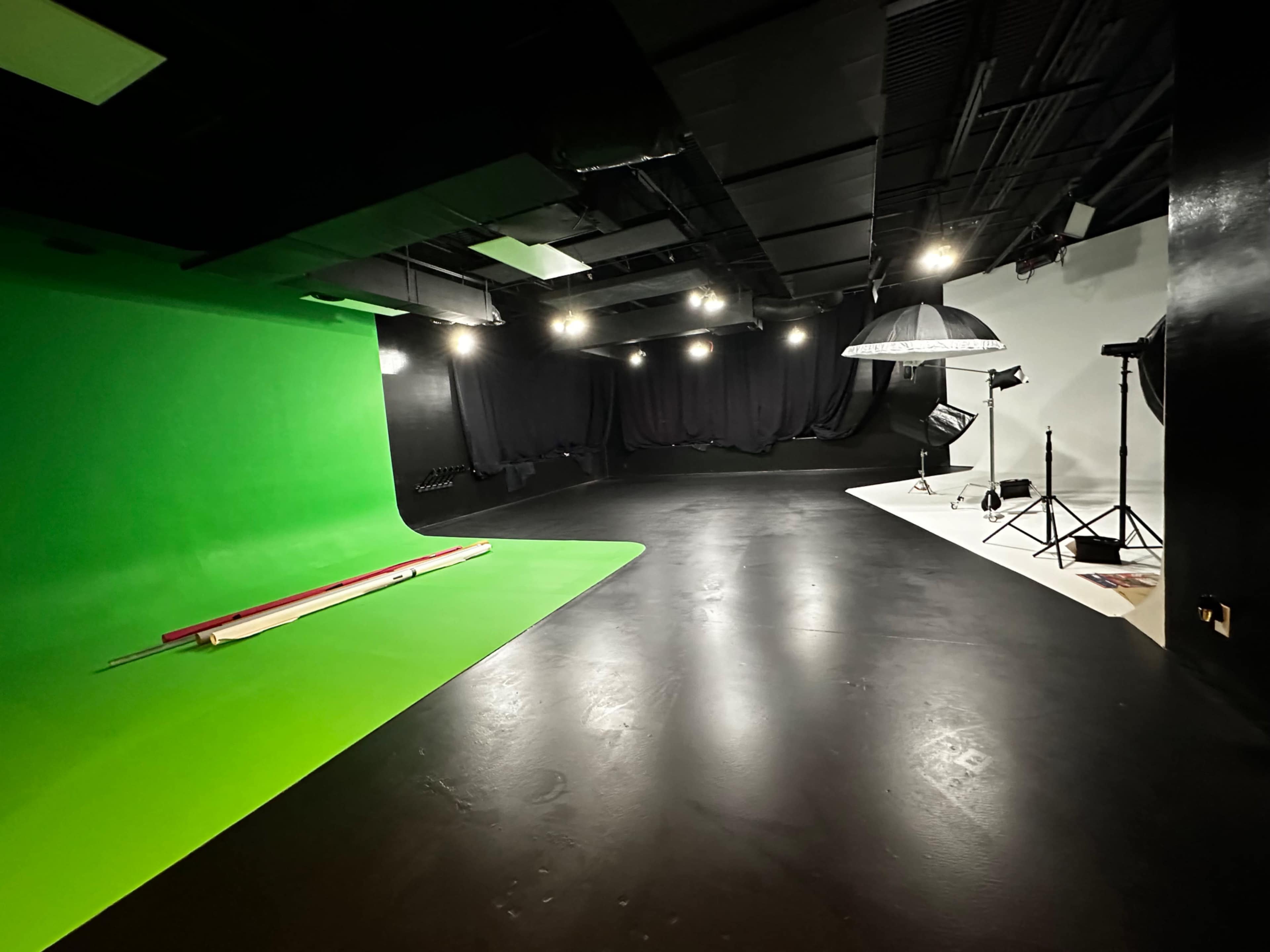 The image shows a studio space divided into two sections: one with a green screen and the other with a white backdrop, equipped with lighting and photography equipment.