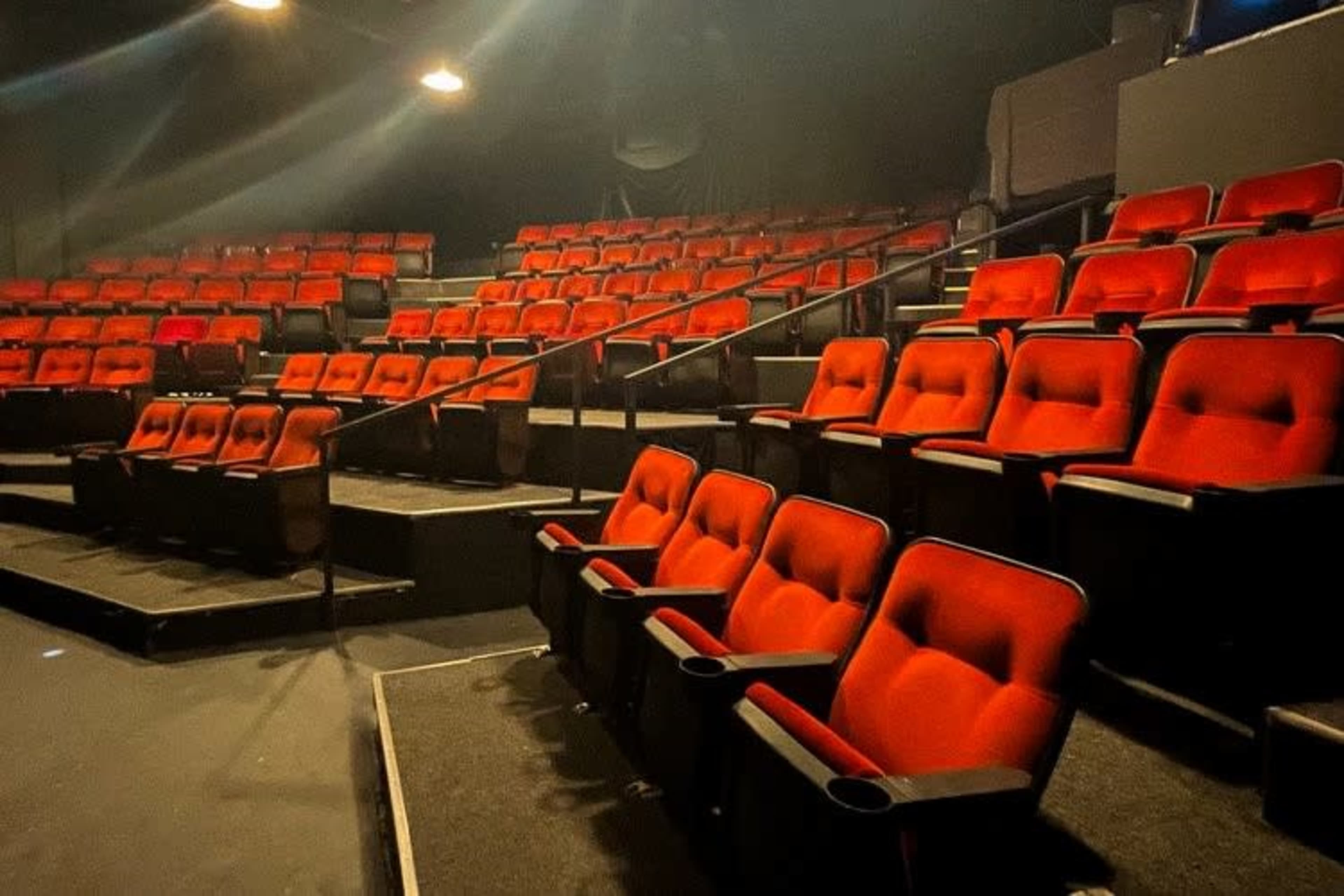 A theater seating area filled with red upholstered chairs arranged in rows on tiered platforms.