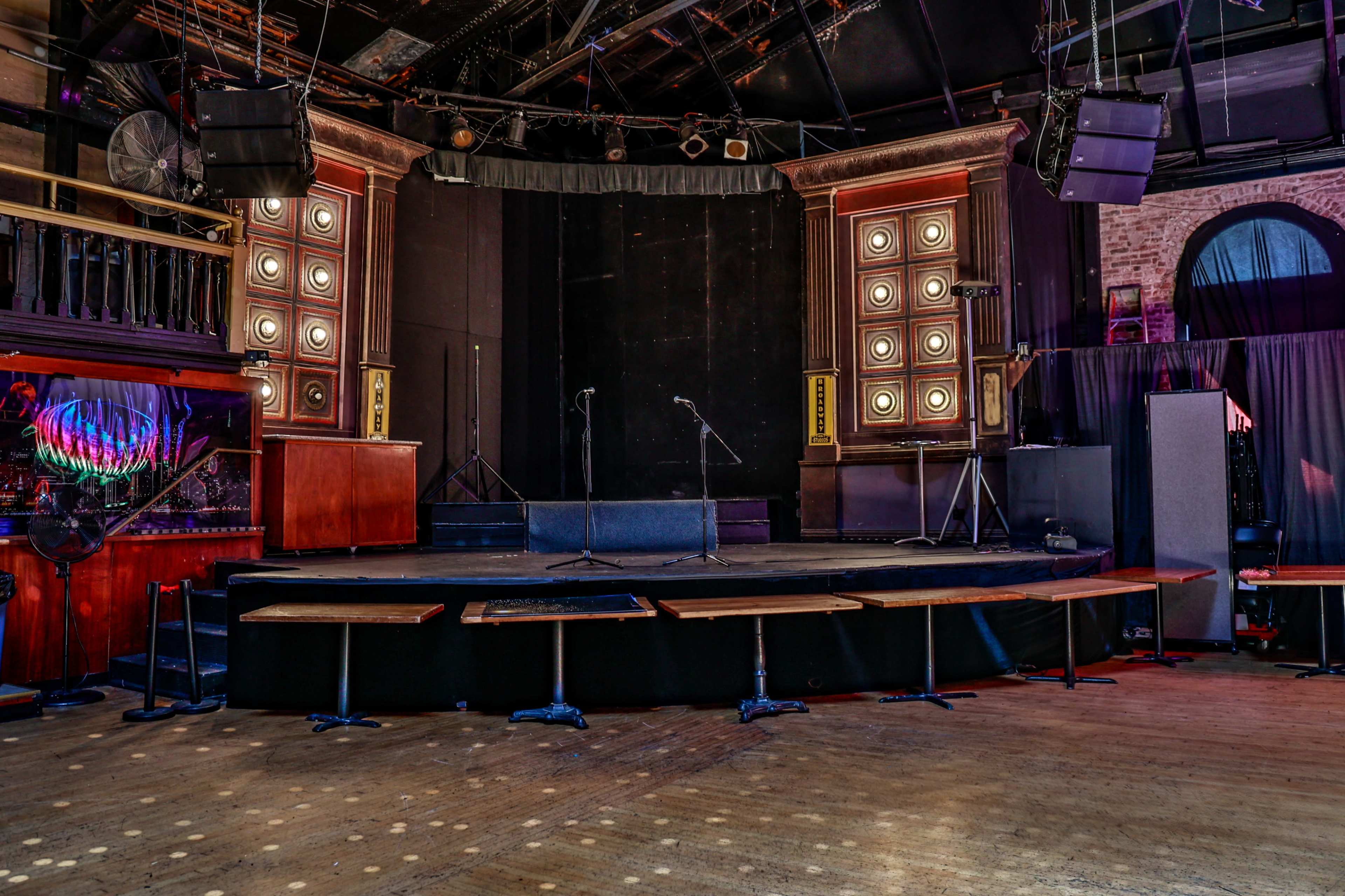The image shows an empty stage set up for a performance, with microphones on stands and seating arranged in front.