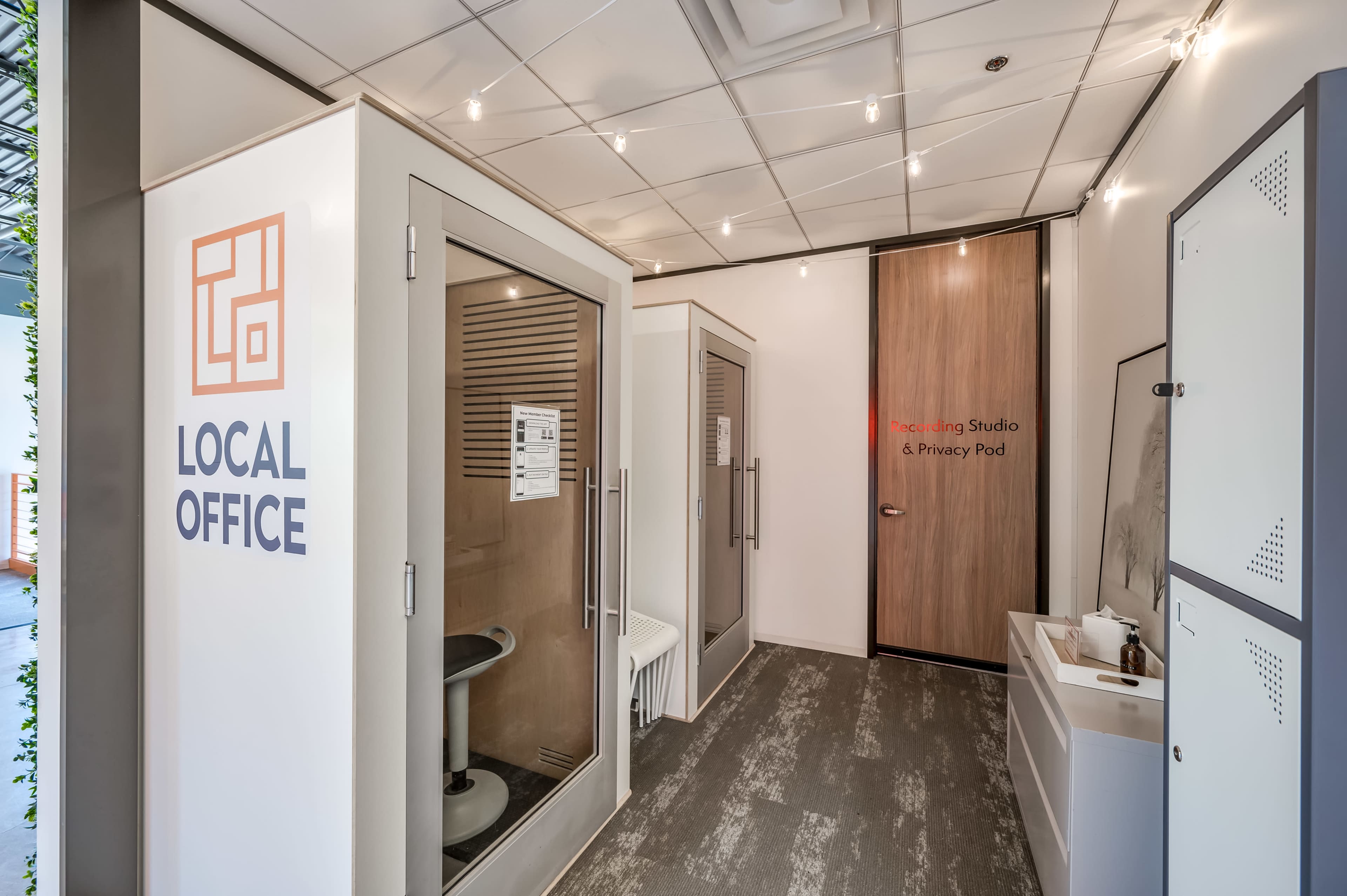 The image shows a modern workspace featuring soundproof booths labeled "Recording Studio & Privacy Pod" and a clean, well-lit entrance area with a sign reading "LOCAL OFFICE."