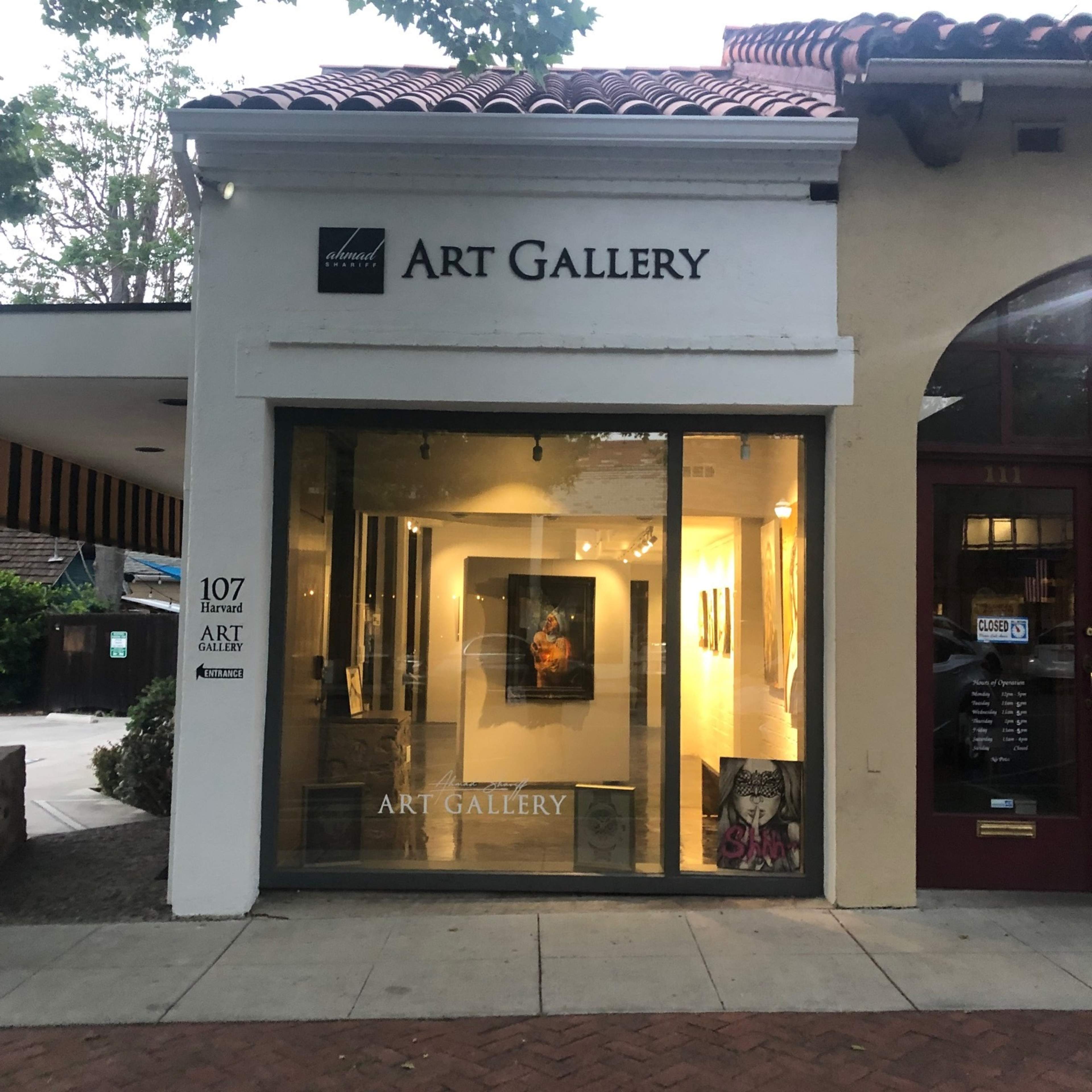 The exterior of an art gallery features large windows showcasing artwork and a sign displaying the name "ART GALLERY" above the entrance.
