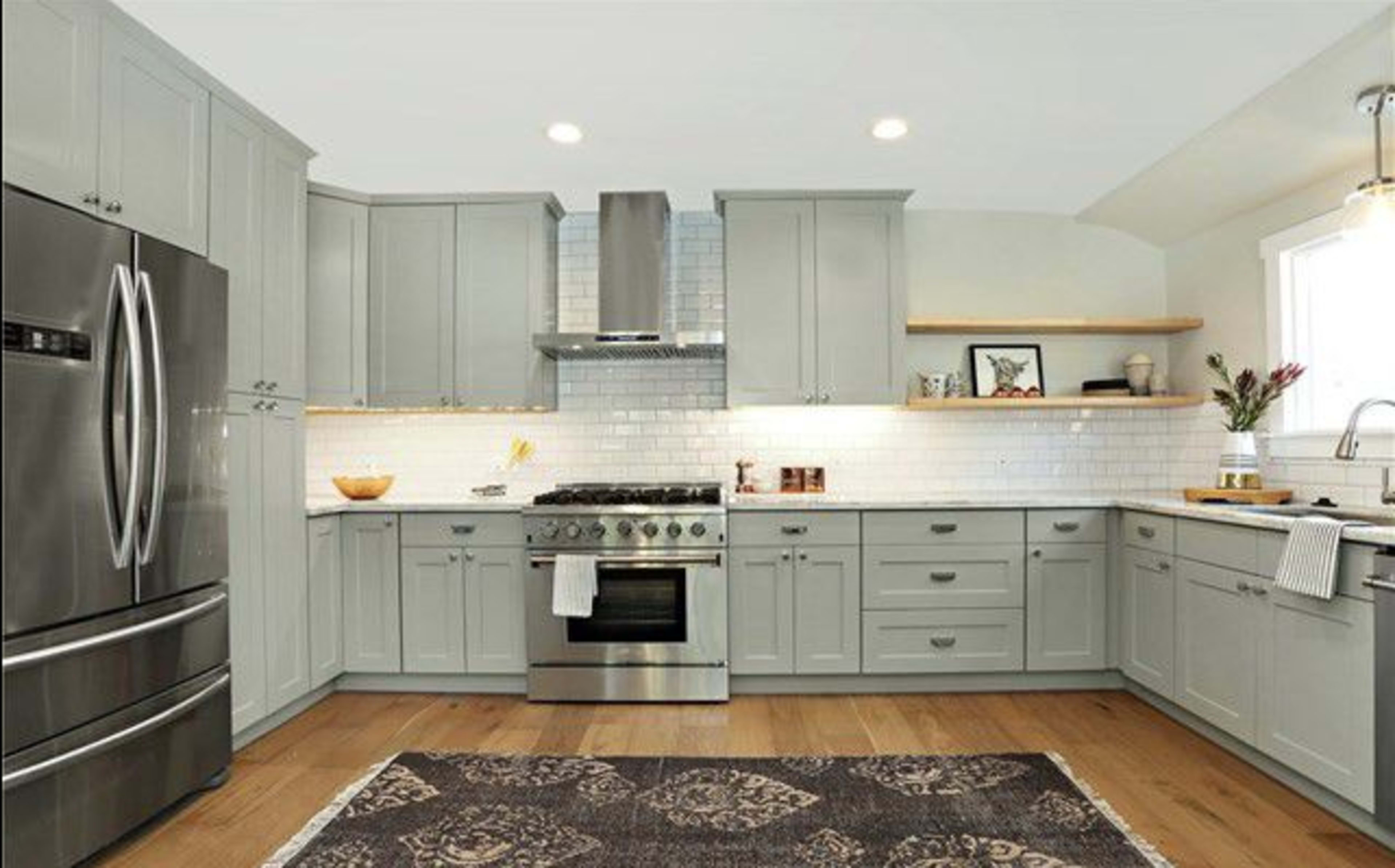 A modern kitchen with gray cabinets, stainless steel appliances, and a white tiled backsplash.