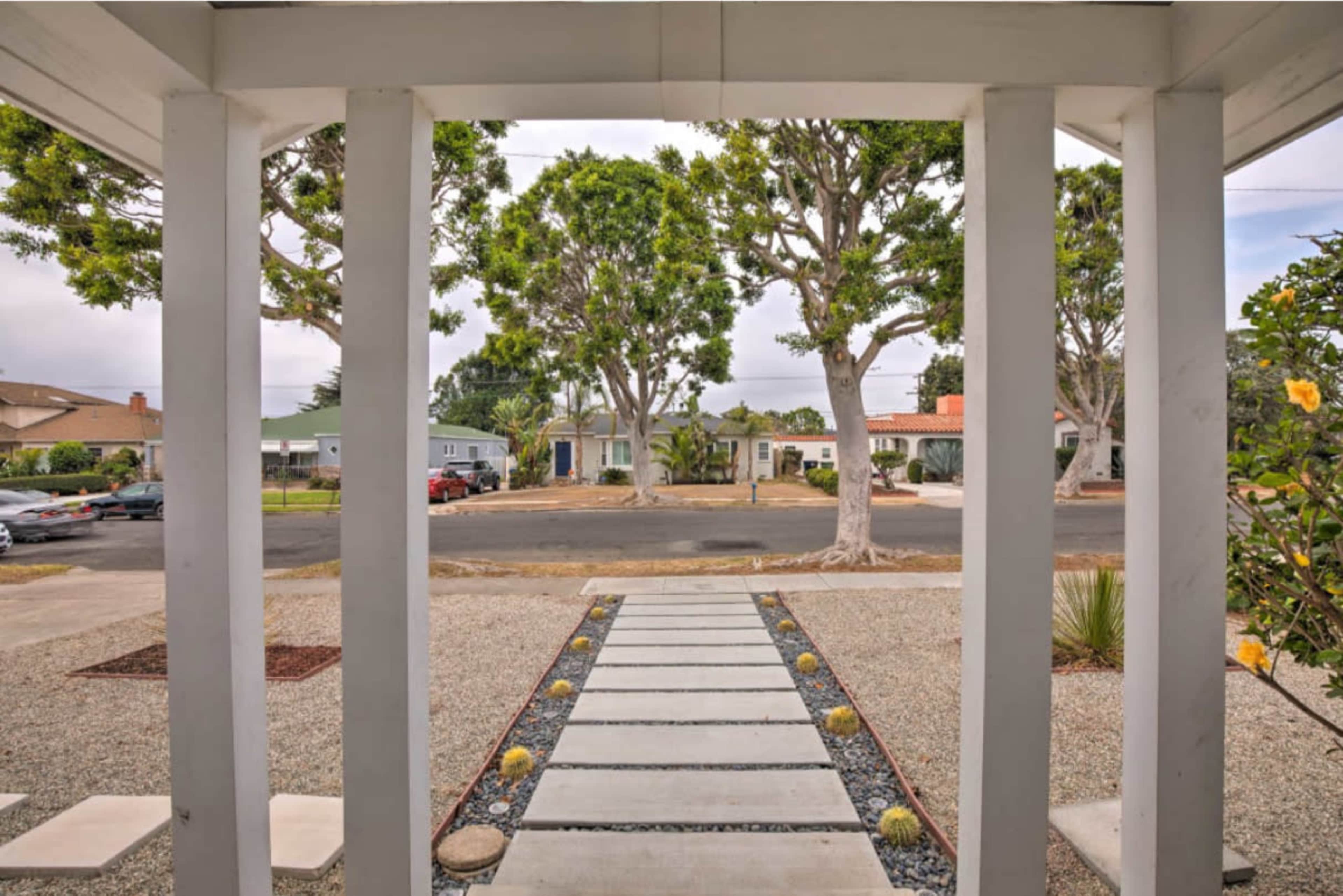 The image shows a pathway leading from a porch to a street lined with trees and houses.