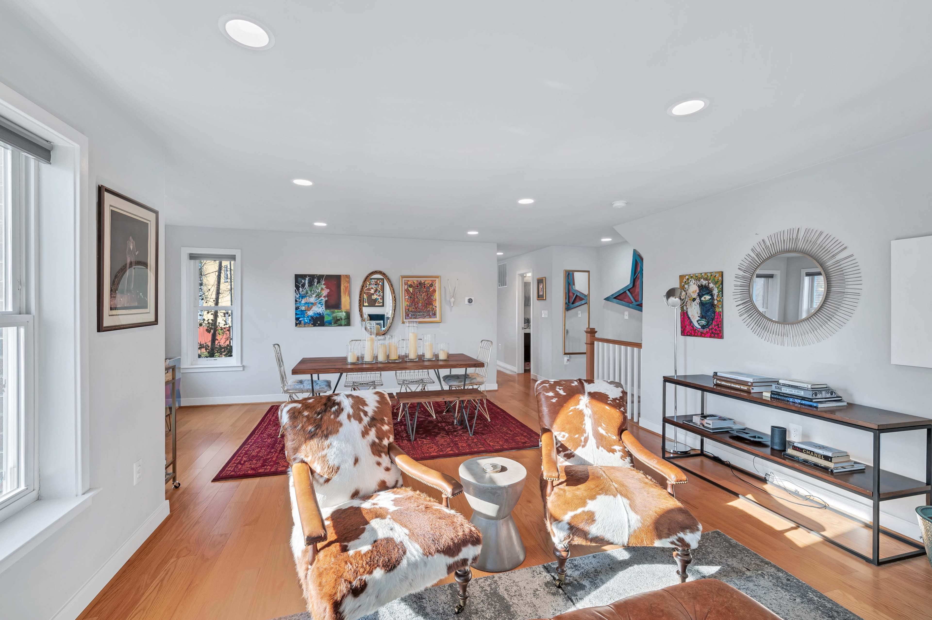 A bright, open living space features two patterned chairs, a dining table, and artwork on the walls.