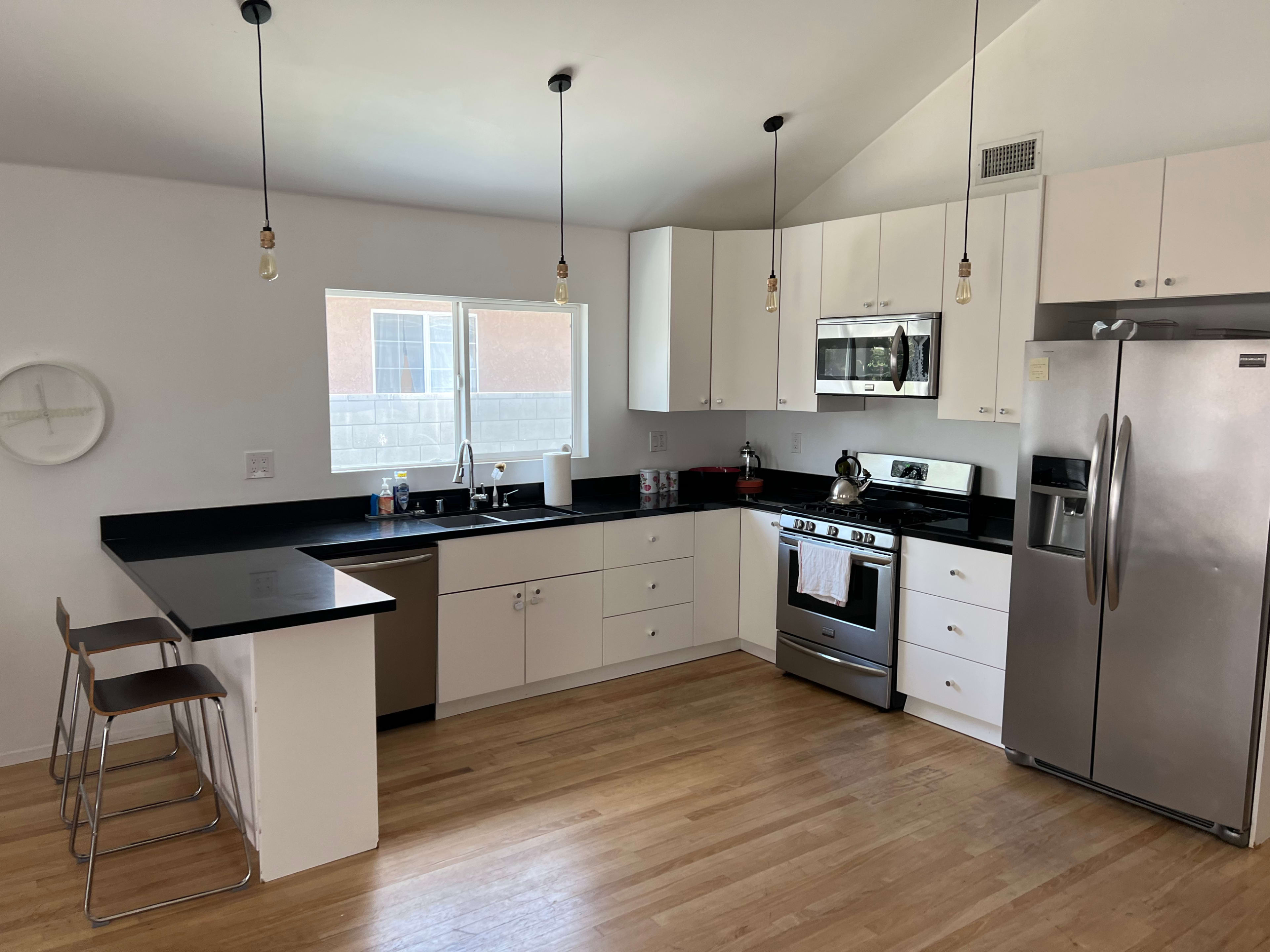 A modern kitchen features a black countertop, stainless steel appliances, and white cabinetry.