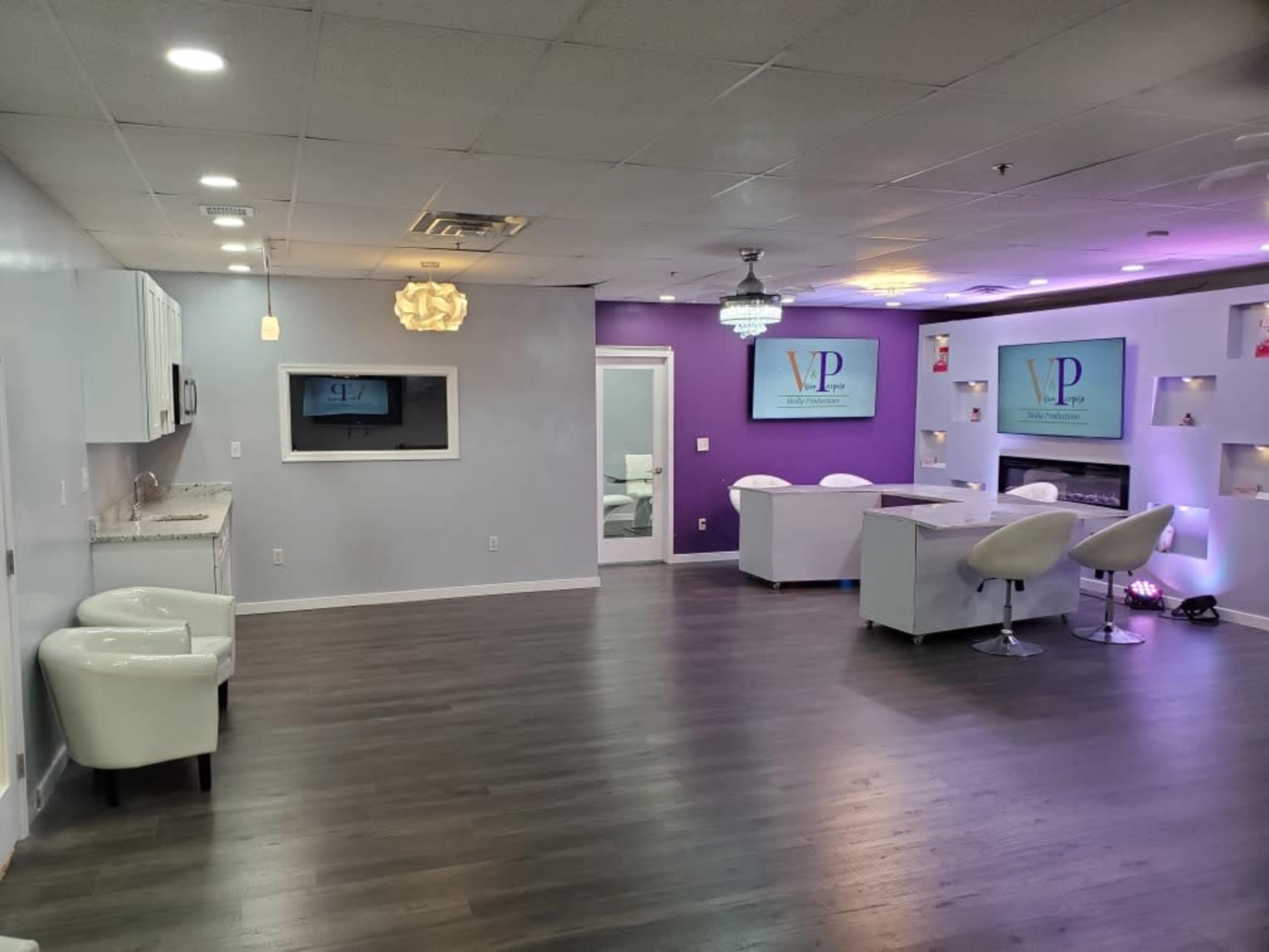A modern, well-lit interior of a cosmetic office features white furniture, purple accent walls, and digital displays.