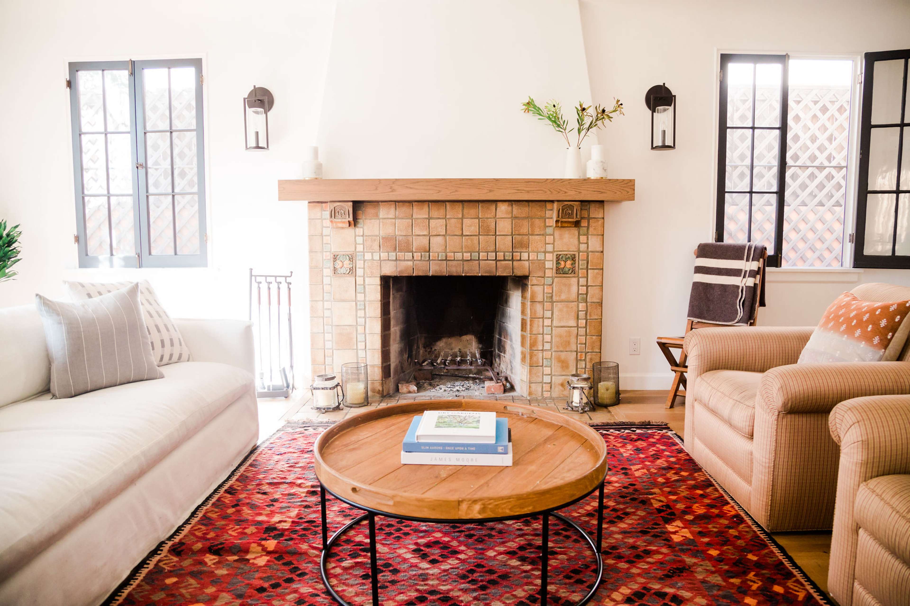 The living room features a fireplace with a tiled surround and a circular wooden coffee table on a patterned rug.