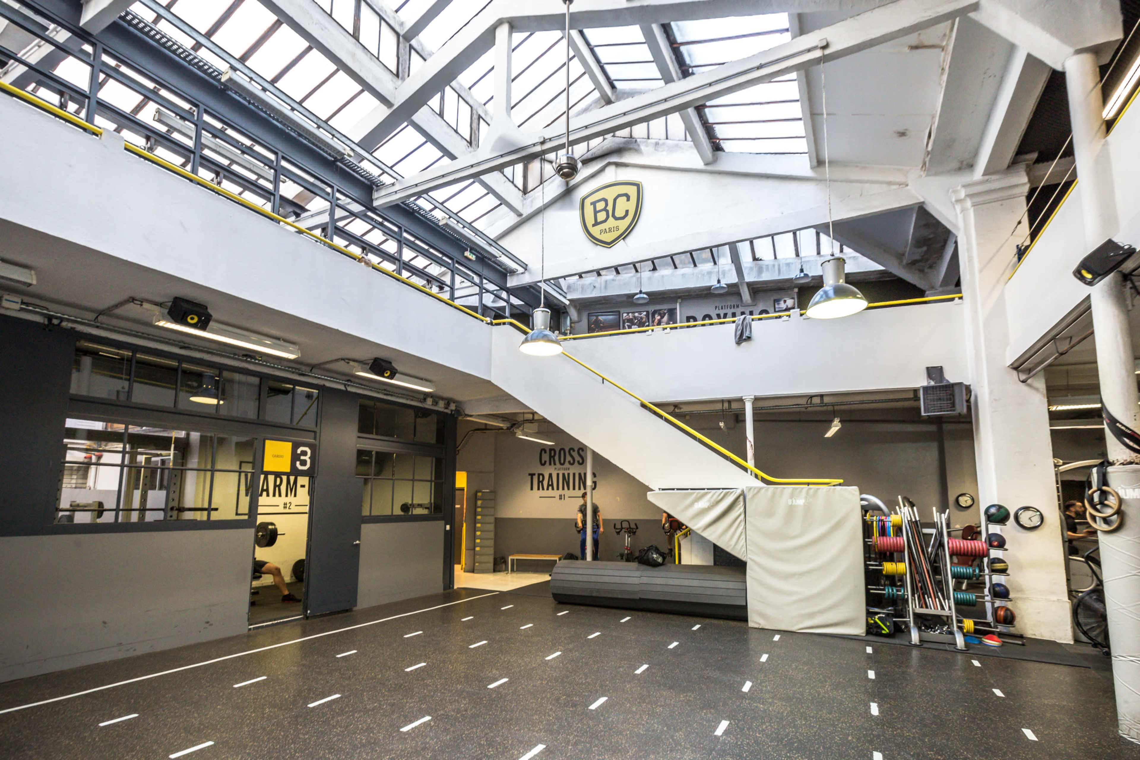 A spacious cross-training gym with a multi-level design, featuring large windows and various fitness equipment.