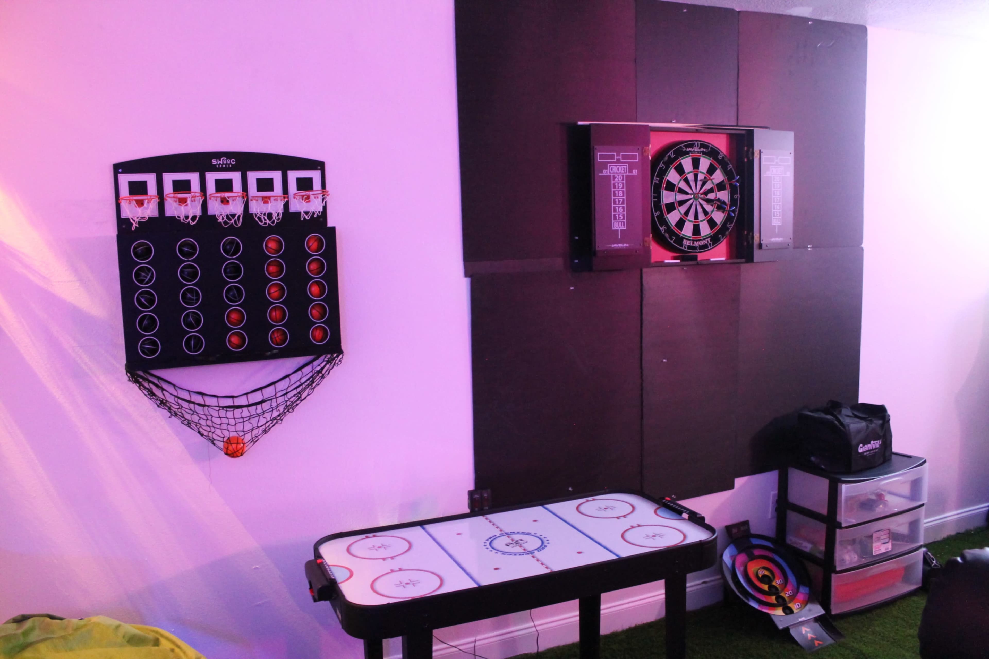 A recreational room featuring a mini basketball game, a dartboard, and an air hockey table.