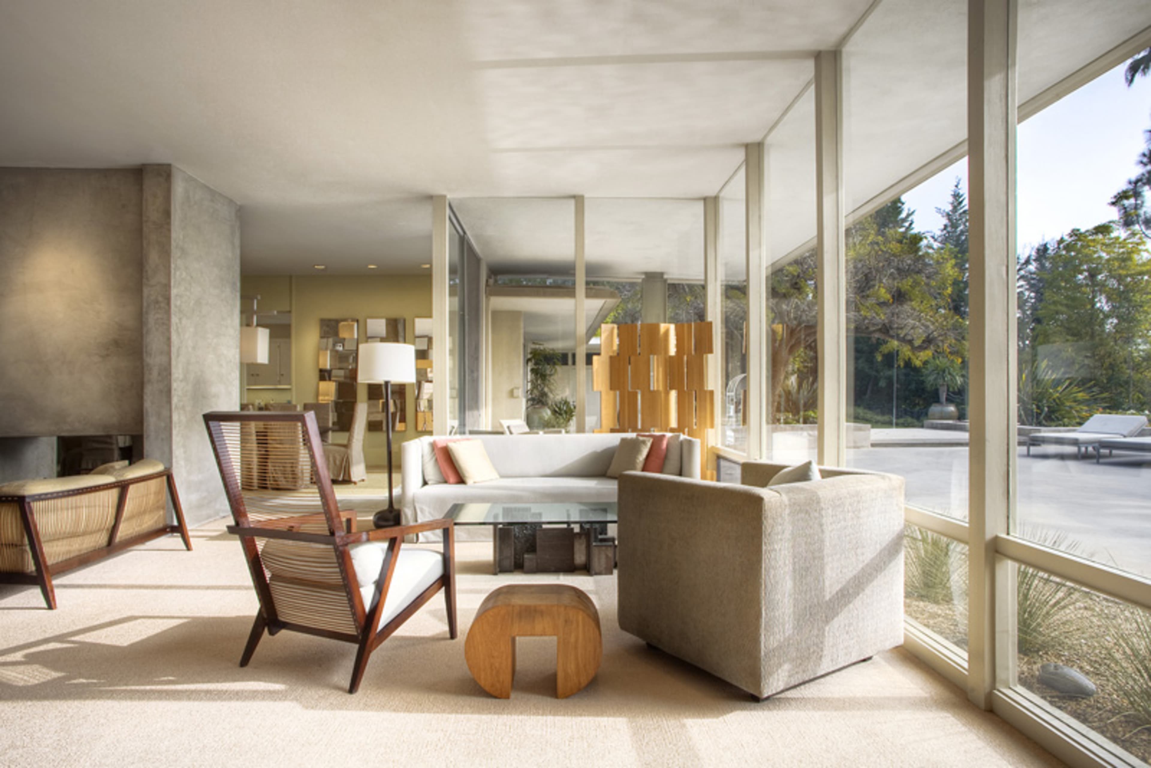 A contemporary living room featuring large windows, modern furniture, and a neutral color palette.