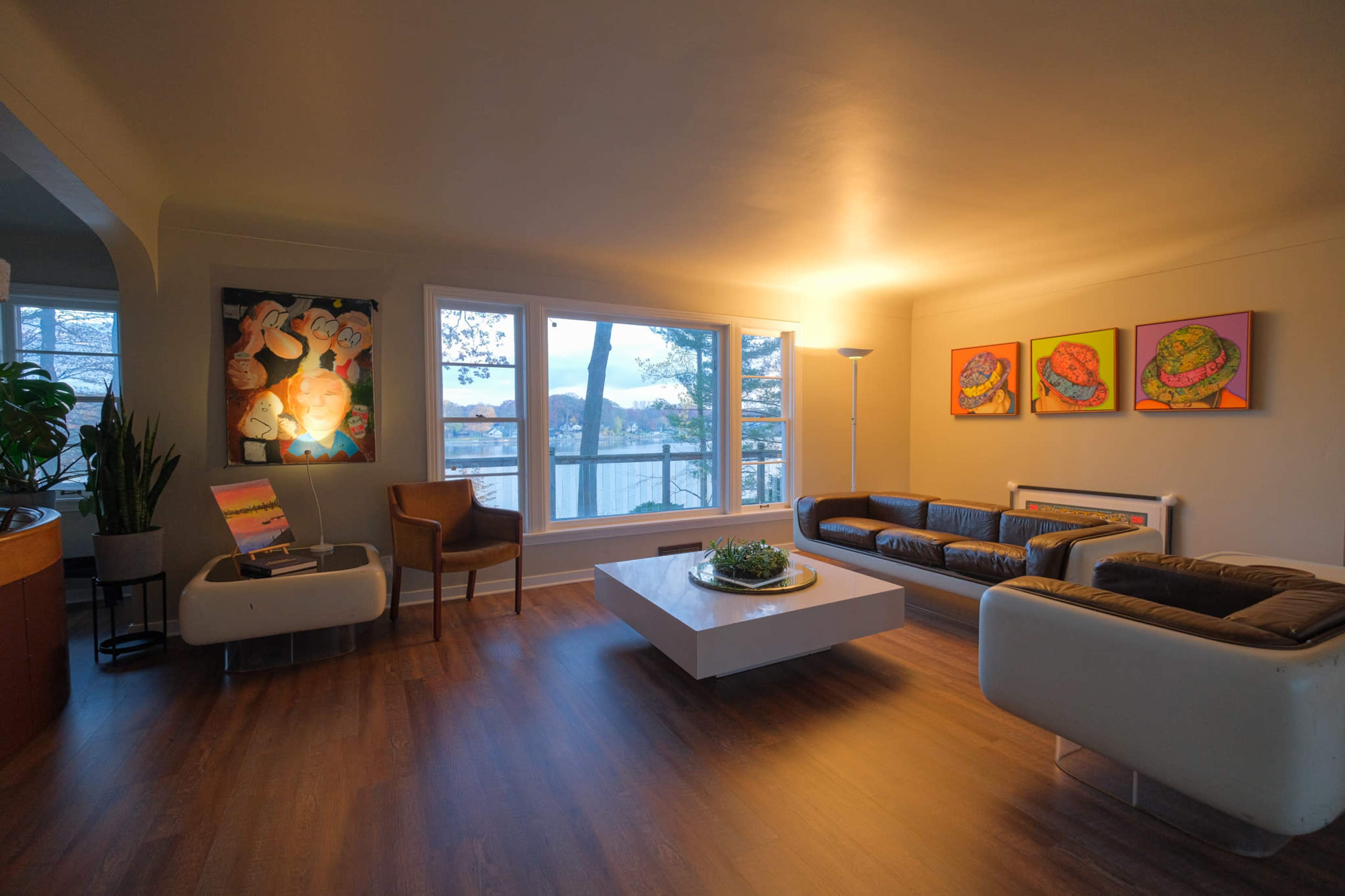 A modern living room features a large window with a view, artistic wall decor, a sleek coffee table, and stylish furniture arranged for comfort.