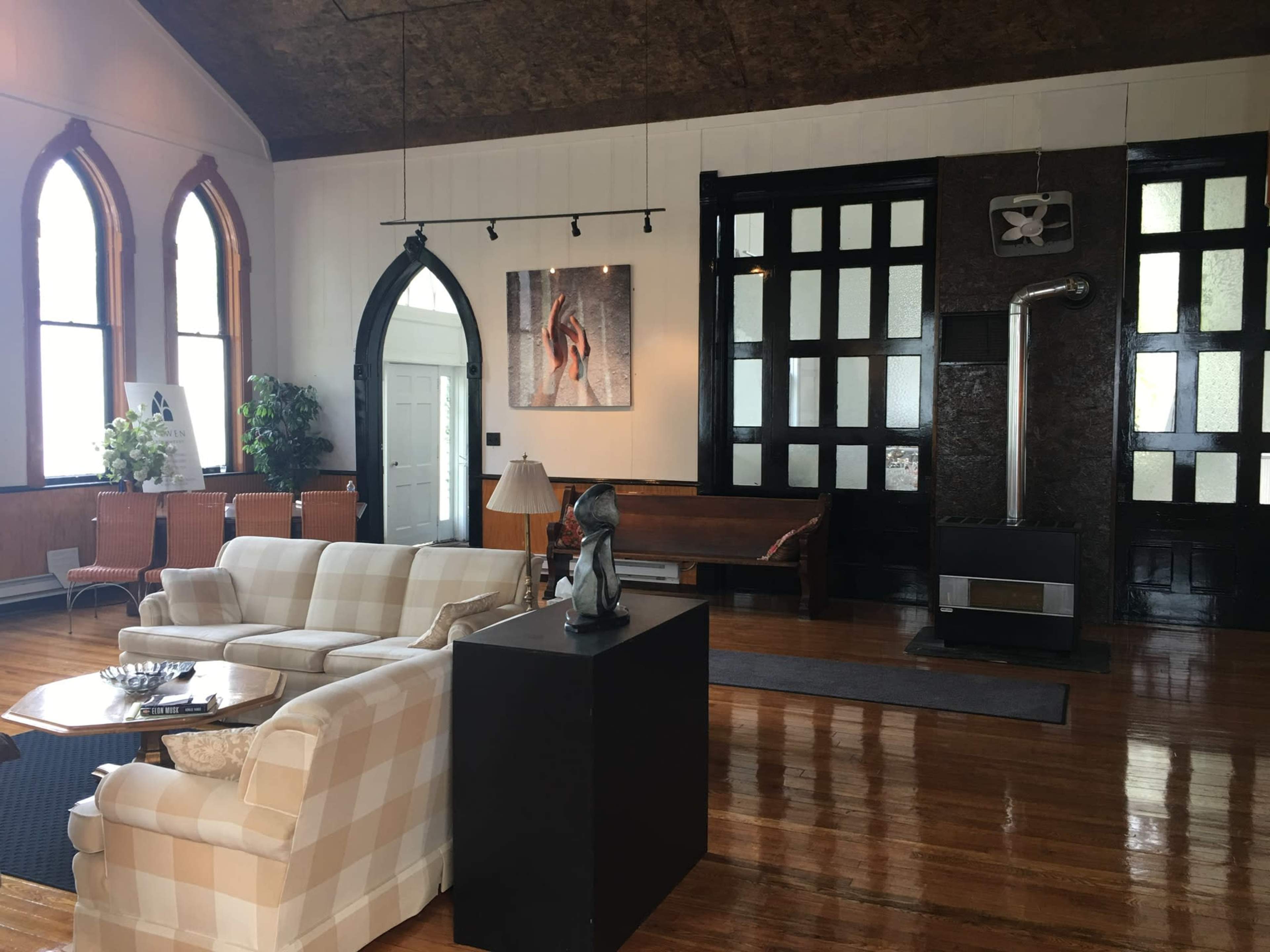 A spacious room with a checkered sofa, a black stand with a sculpture, and large arched windows, highlighting a mix of modern and classic architectural elements.