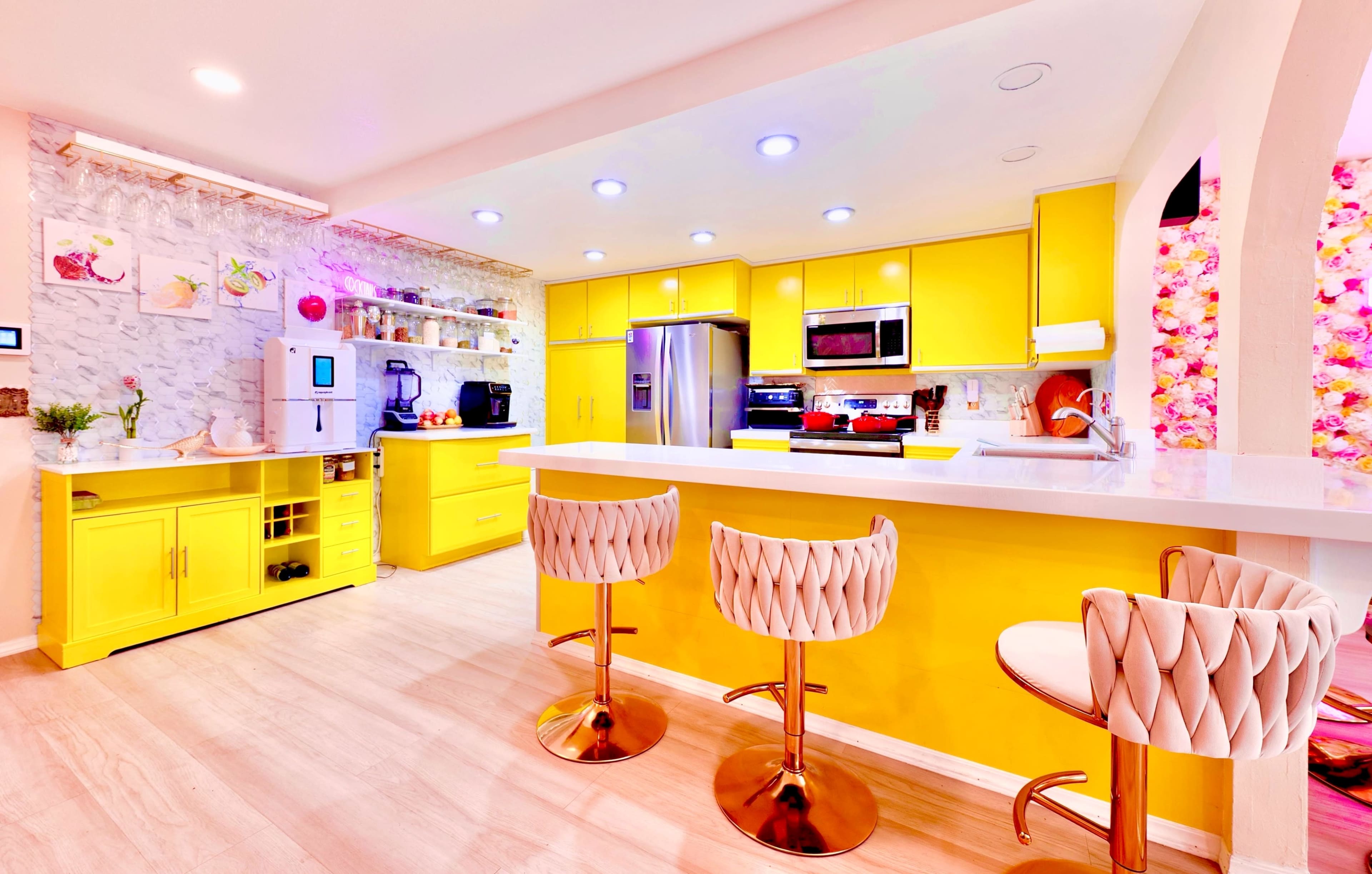 The kitchen features bright yellow cabinets, a central island with seating, and modern appliances.
