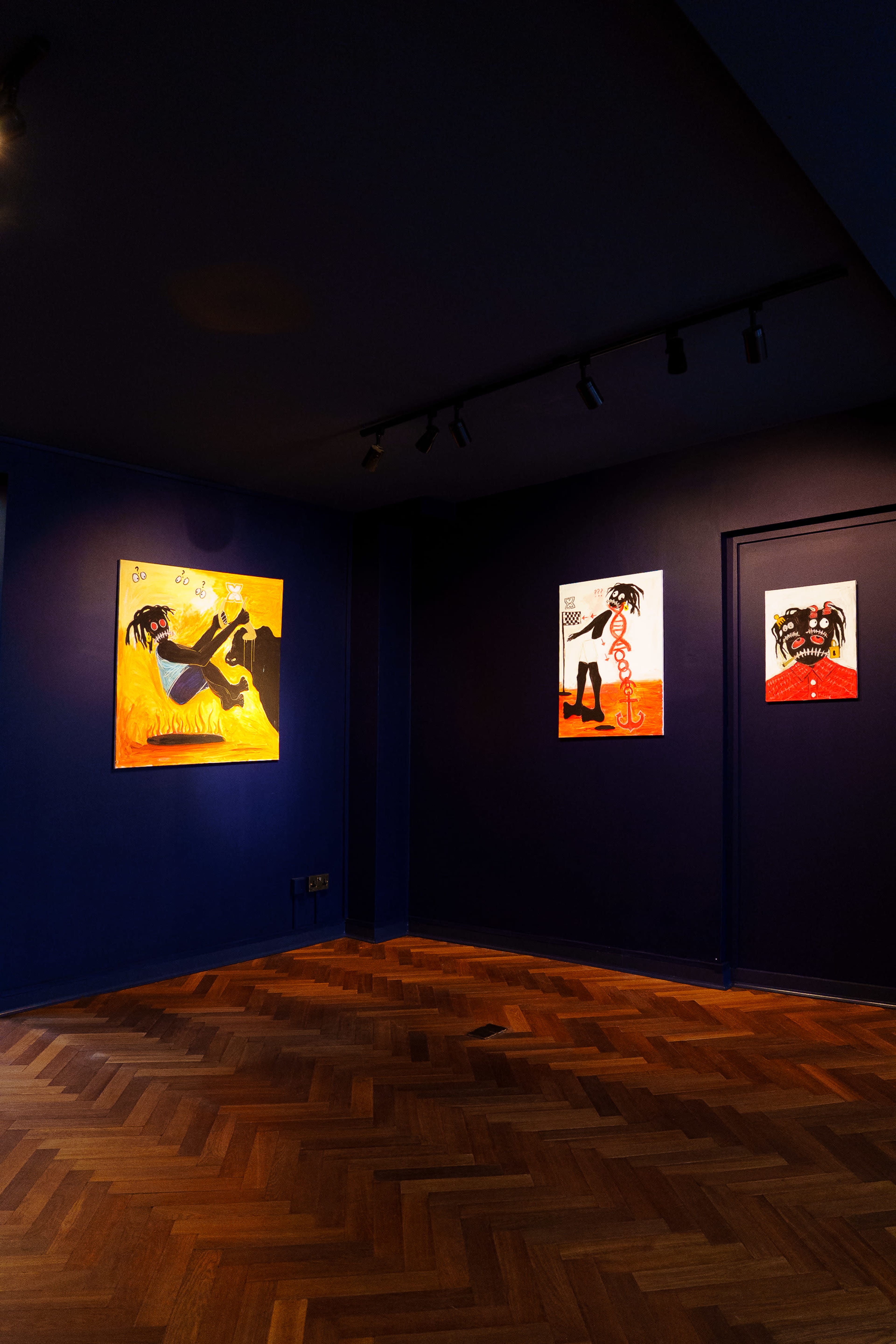 The image depicts an art gallery interior featuring three colorful paintings mounted on dark blue walls, with wooden flooring illuminated by overhead lights.