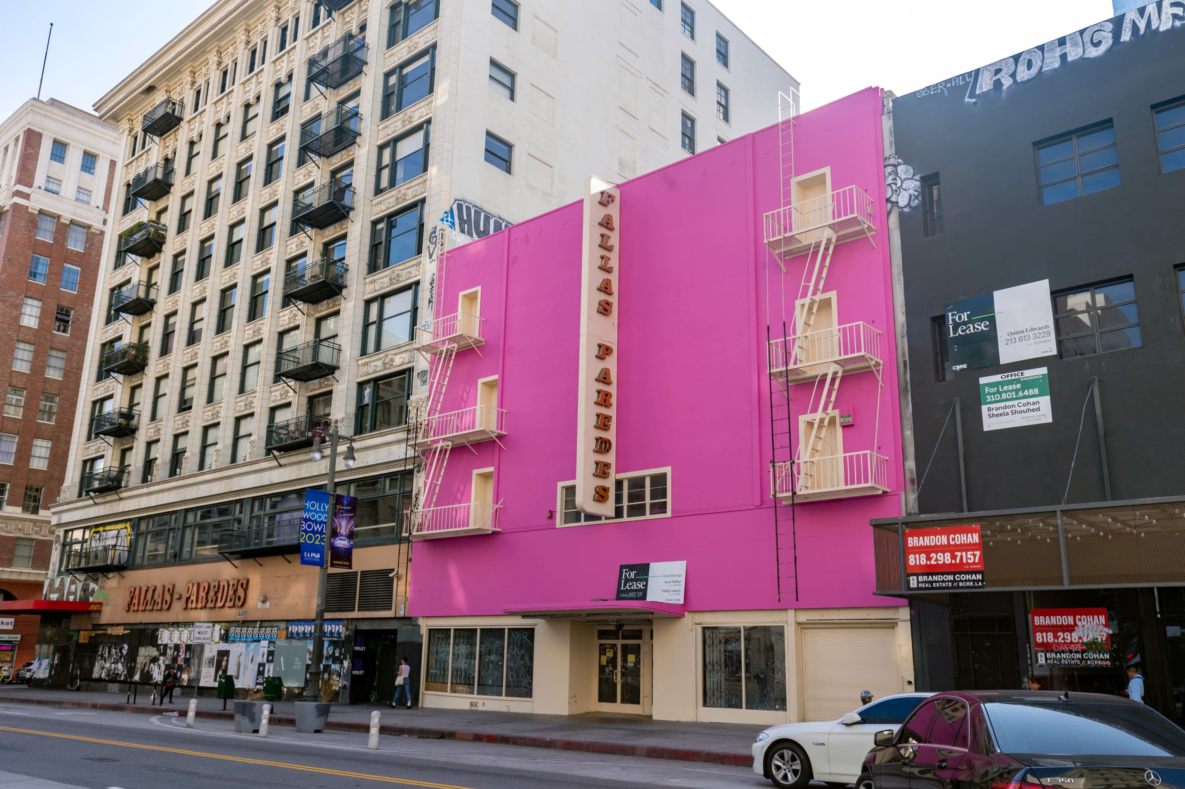 The image shows a pink building named "Dallas Parades" with fire escapes, located between two other commercial buildings on a city street.