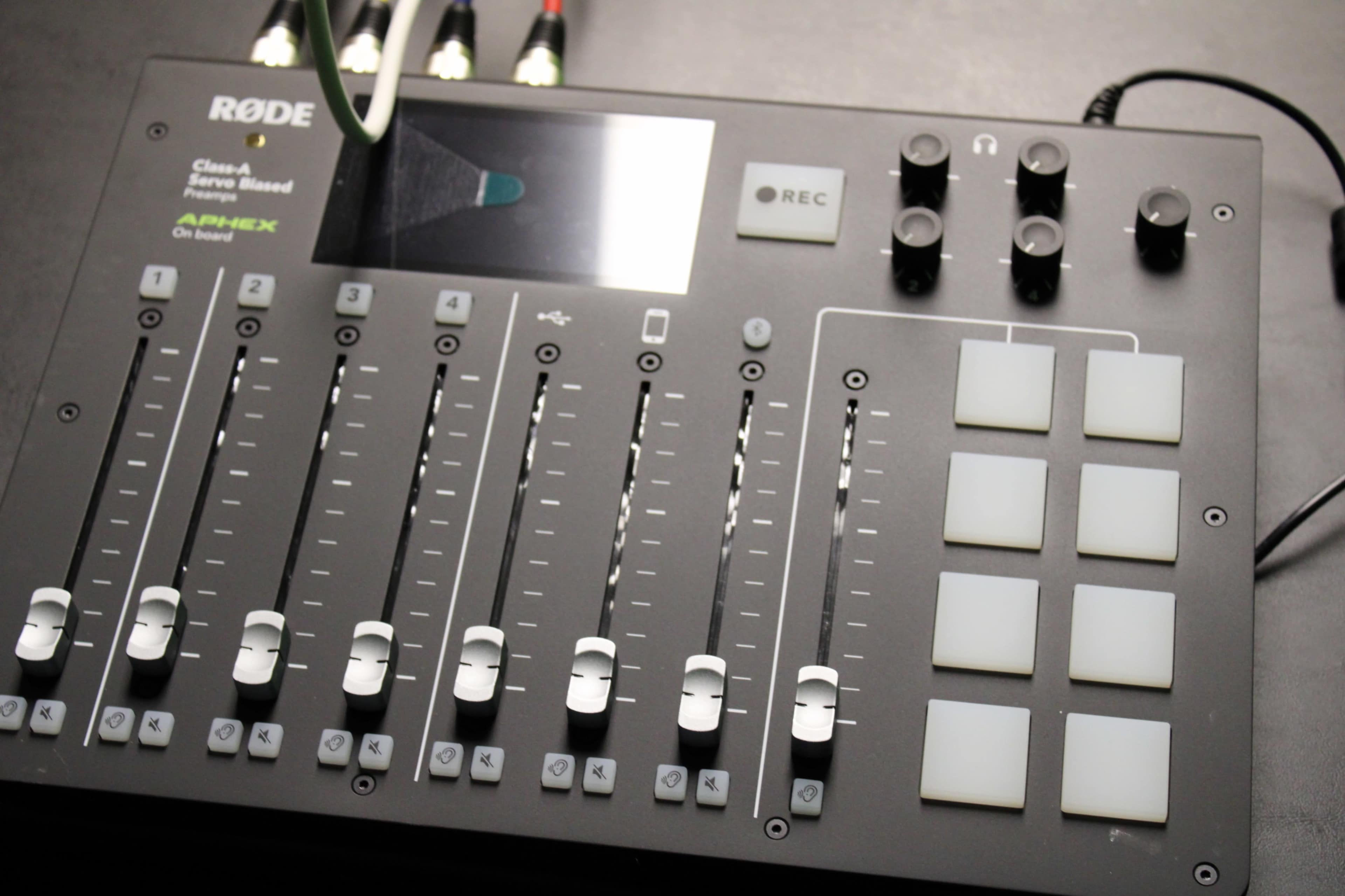 A Rode audio mixer with multiple faders, buttons, and a digital display.