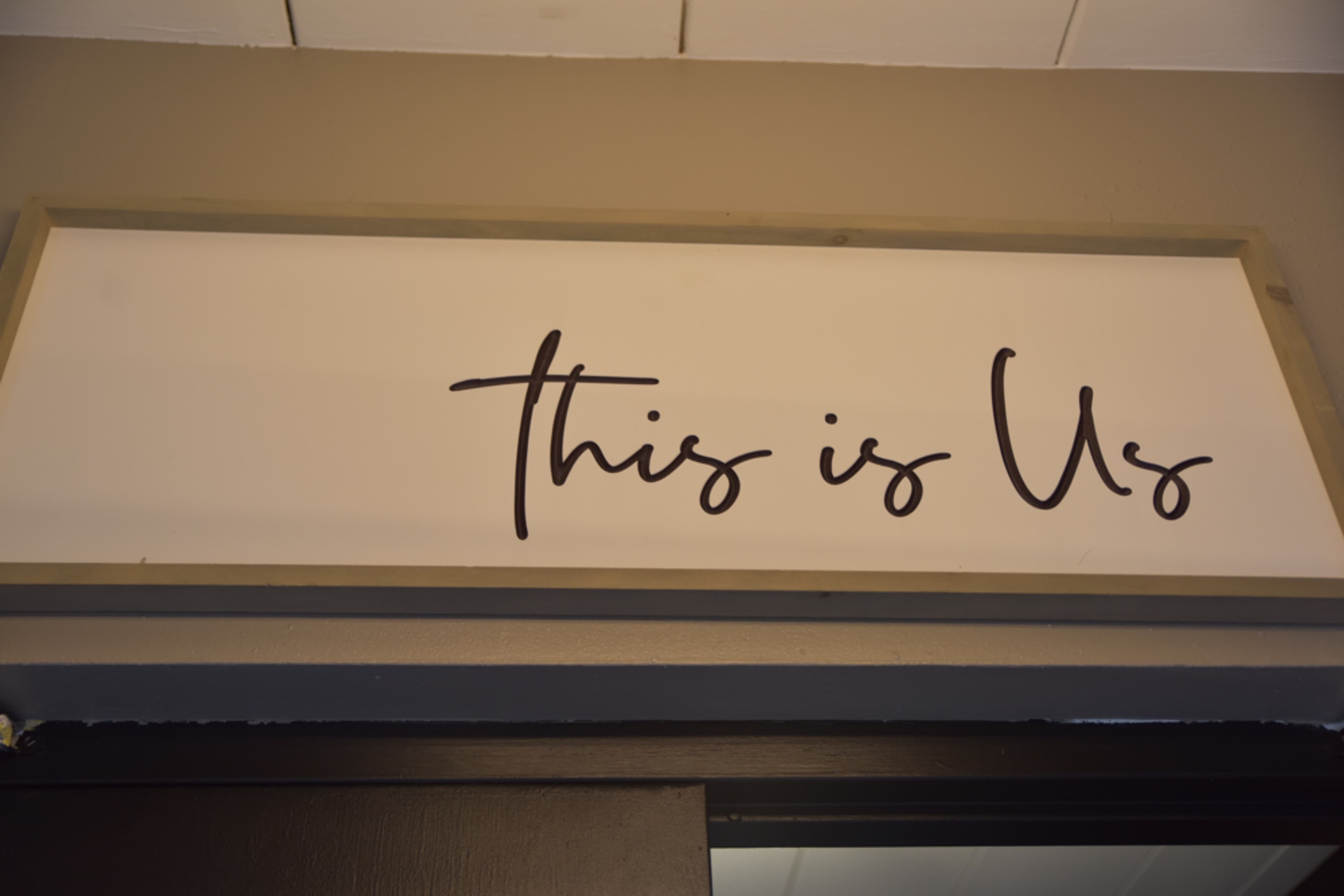 A wooden sign with the phrase "this is Us" is displayed above a doorway.