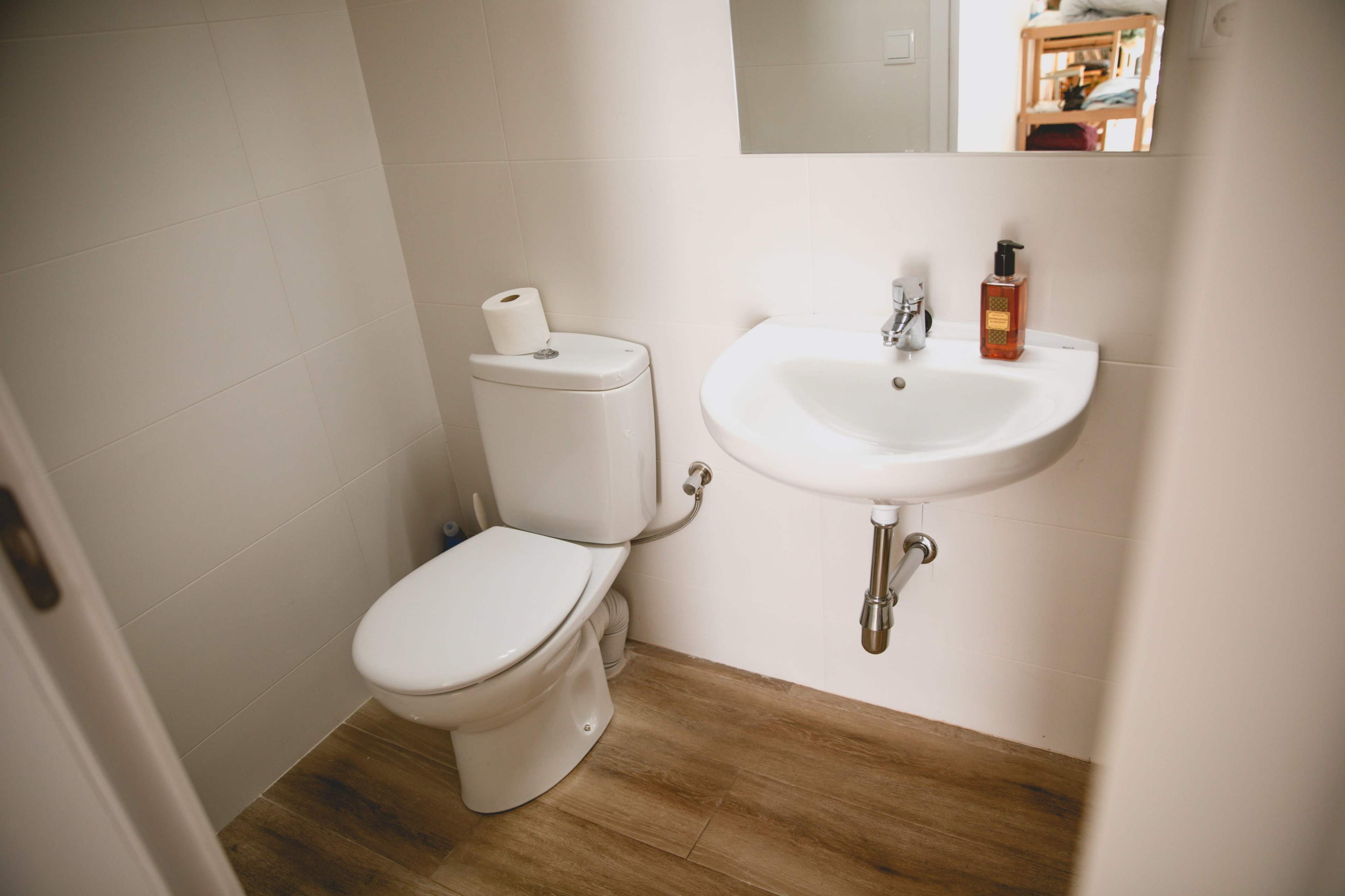 A small, modern bathroom featuring a toilet, a wall-mounted sink, and a mirror.
