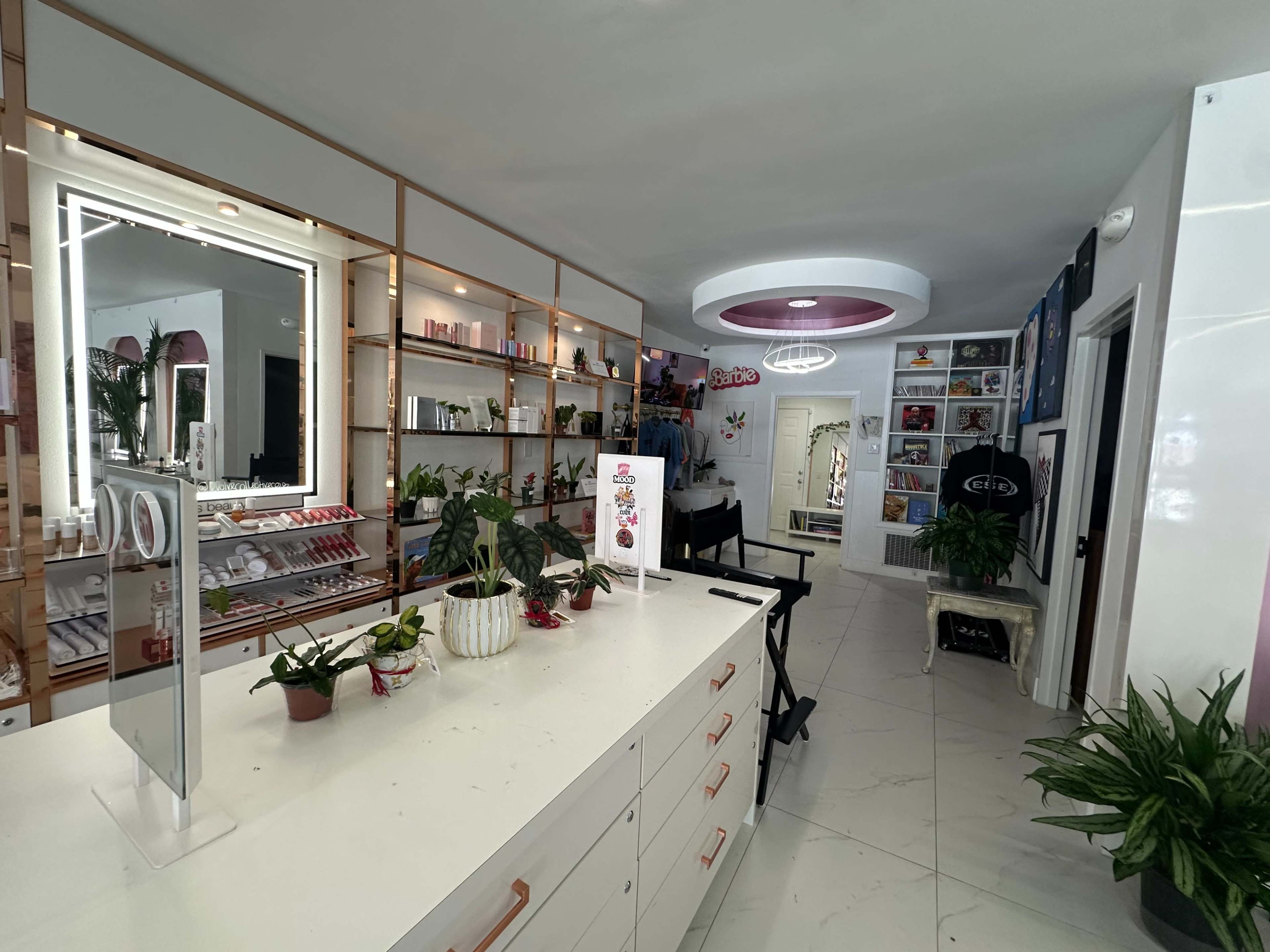 The image shows a modern beauty shop interior with shelves of cosmetic products, plants, and a bright circular light fixture.