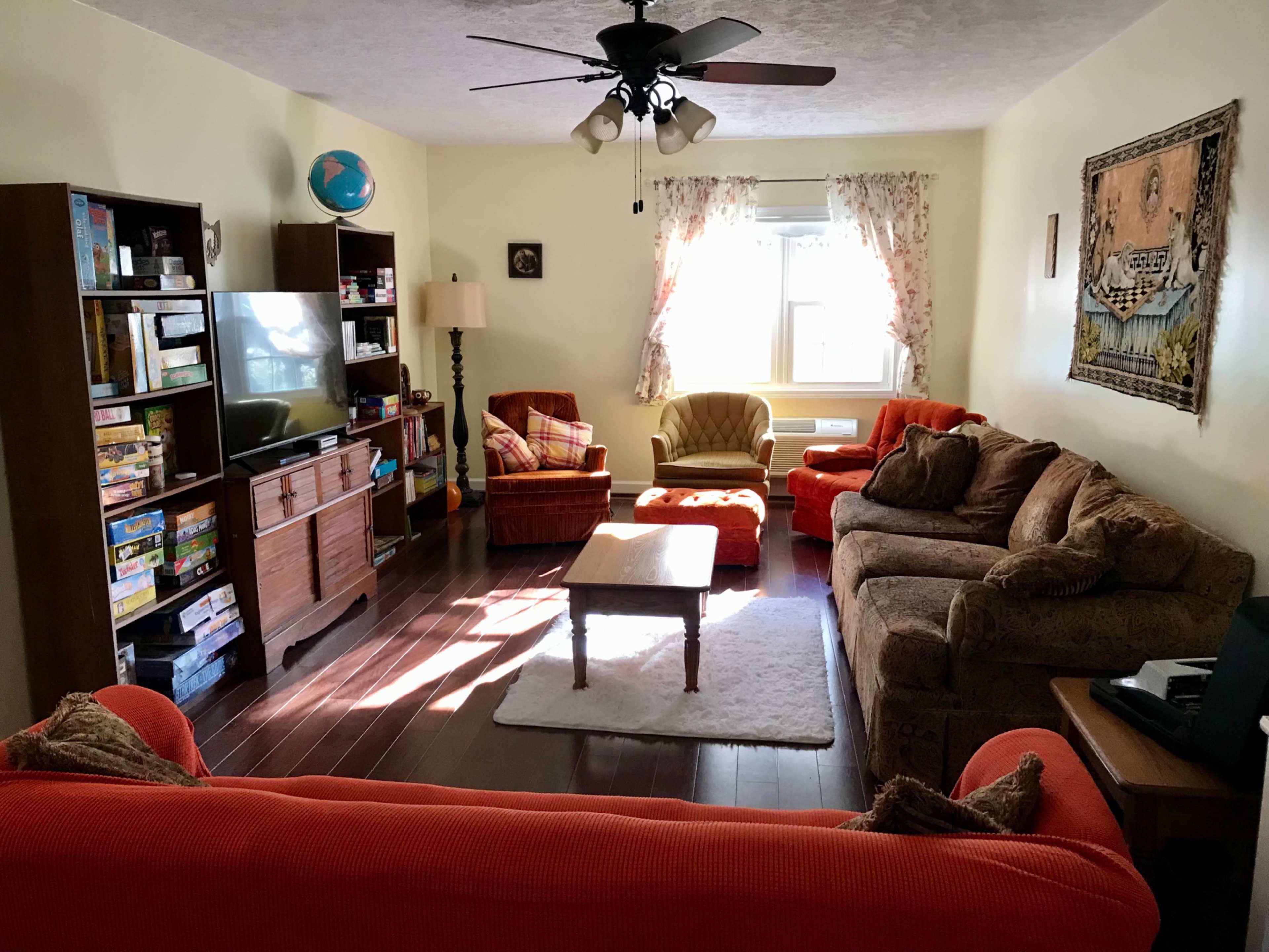A living room with a variety of seating, a coffee table, a television, and bookshelves filled with games and books.