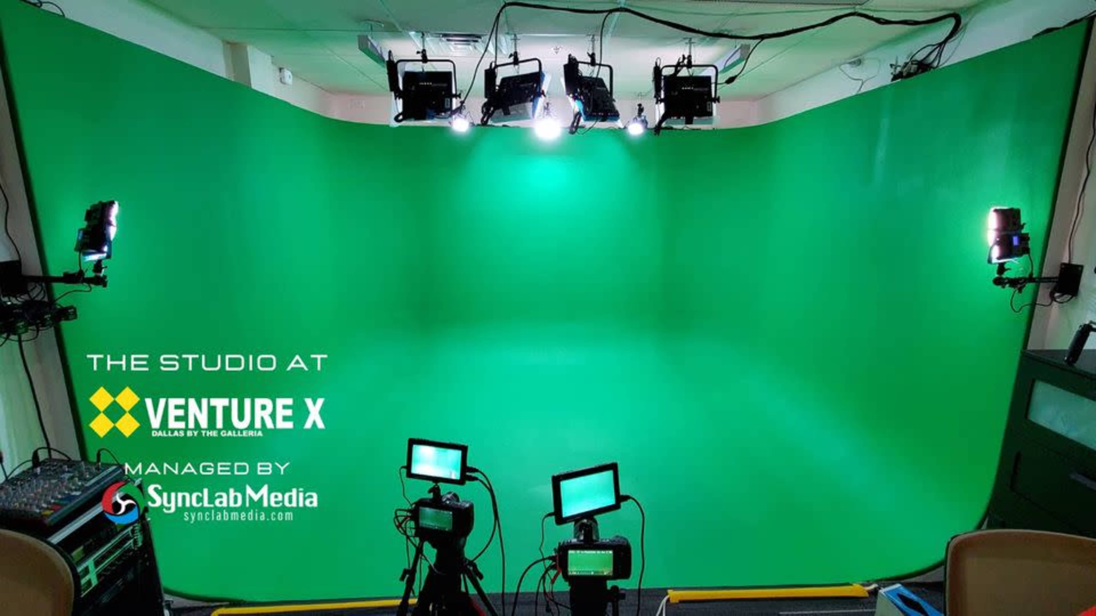 A green screen studio space equipped with multiple lights and cameras.