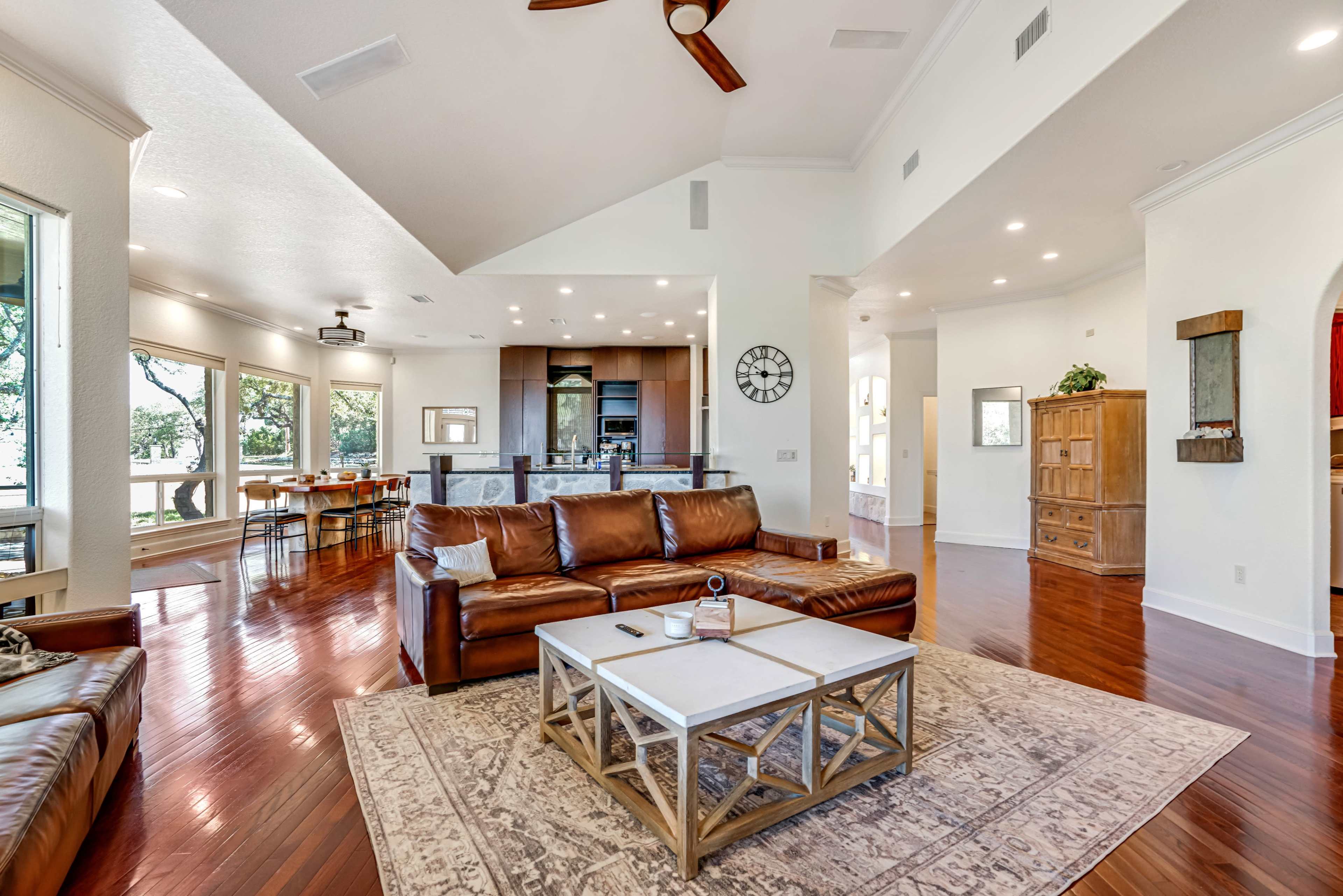 A spacious living area with leather furniture, a coffee table, and large windows that offer a view of the outdoors.