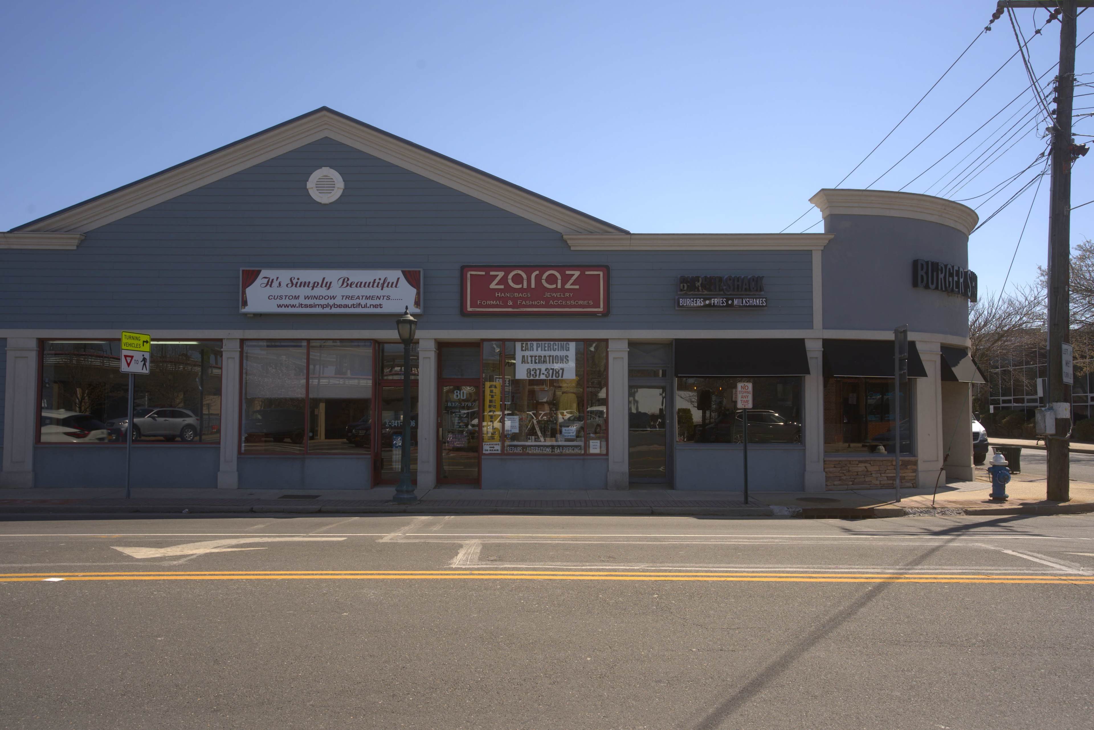 The image shows a small shopping plaza on a sunny day with several storefronts, including a beauty shop and a restaurant called "Zaraz."