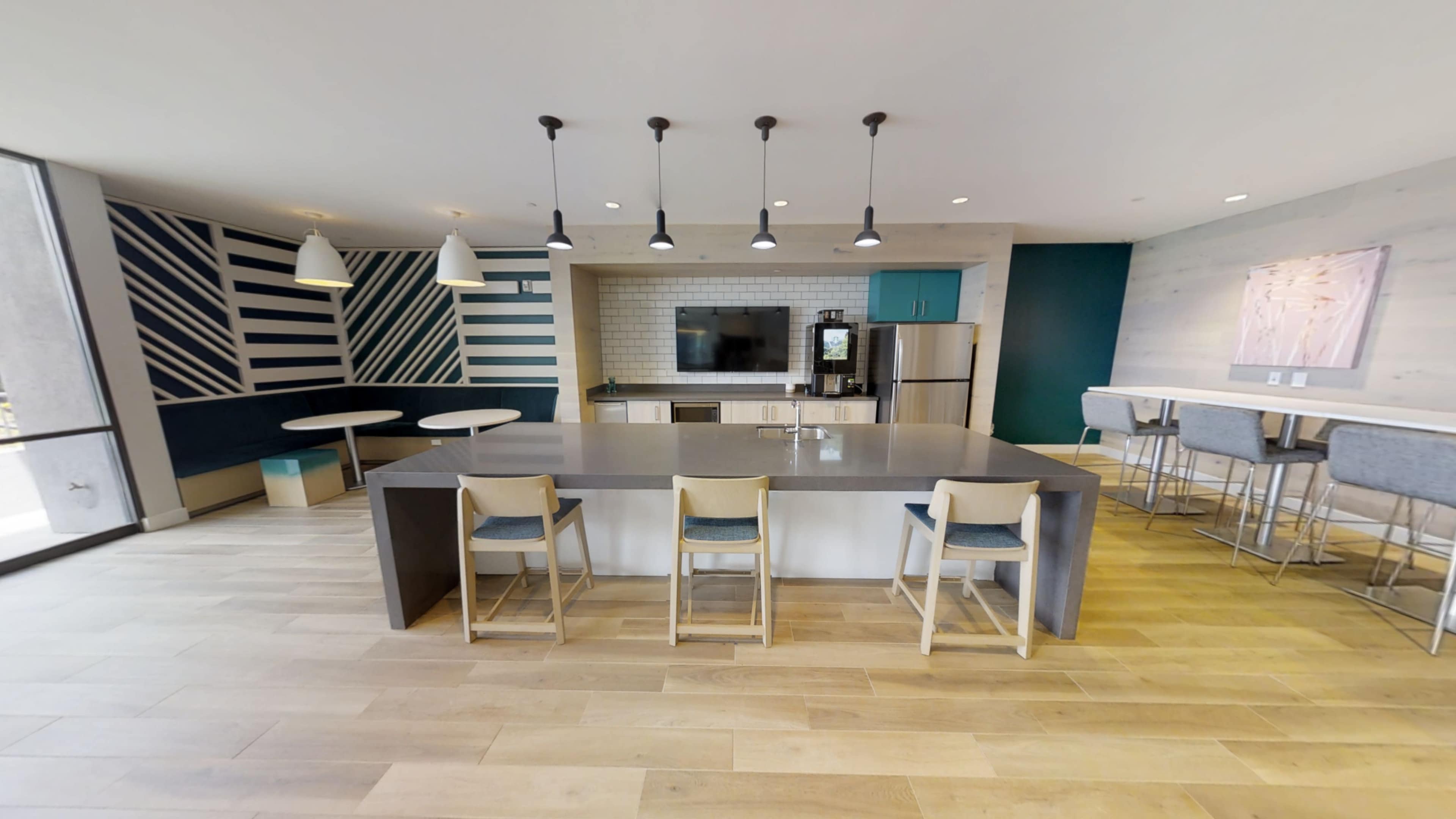 A modern kitchen area with a central island, bar stools, and a seating area featuring striped walls.