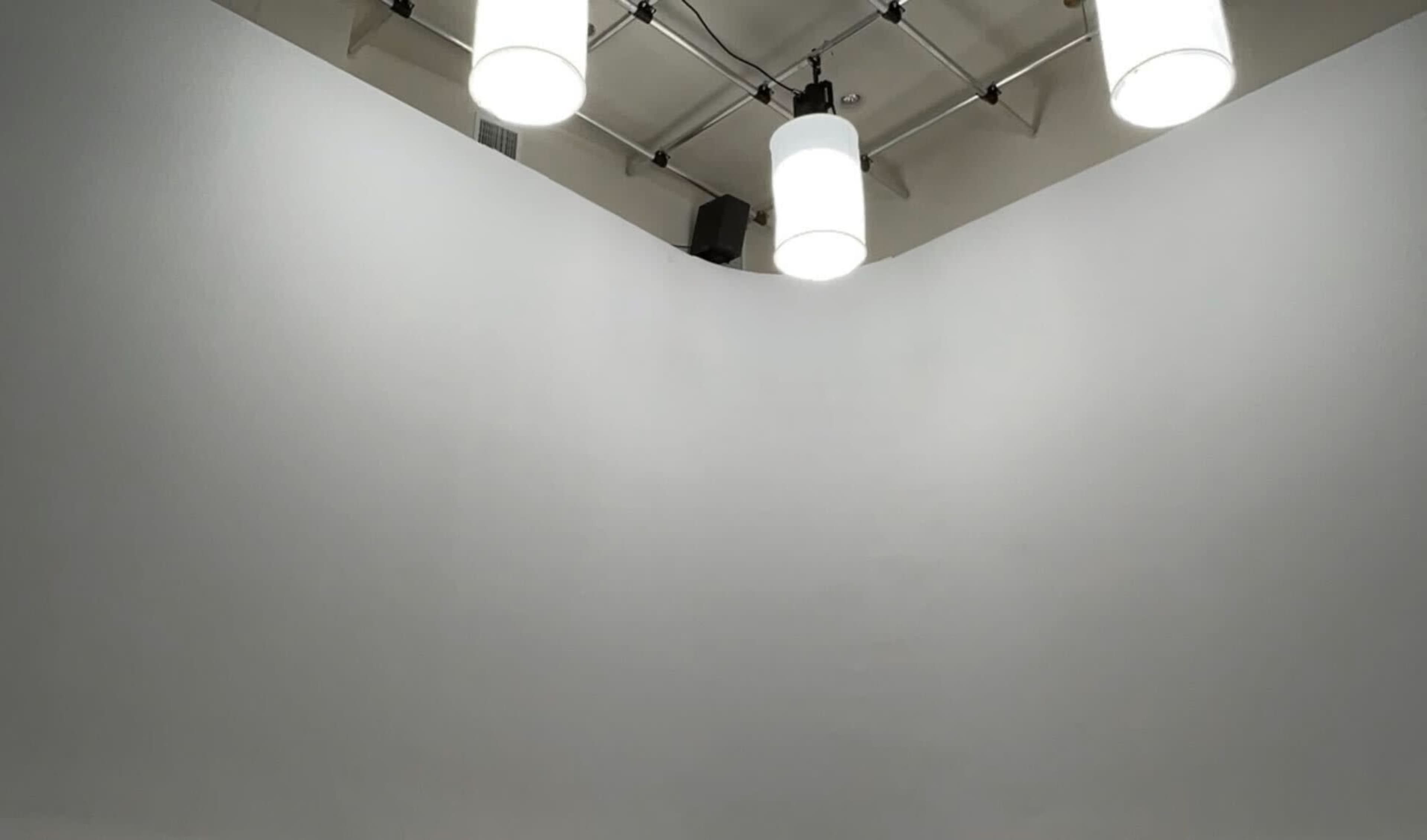 A ceiling with four hanging pendant lights above a curved white wall.