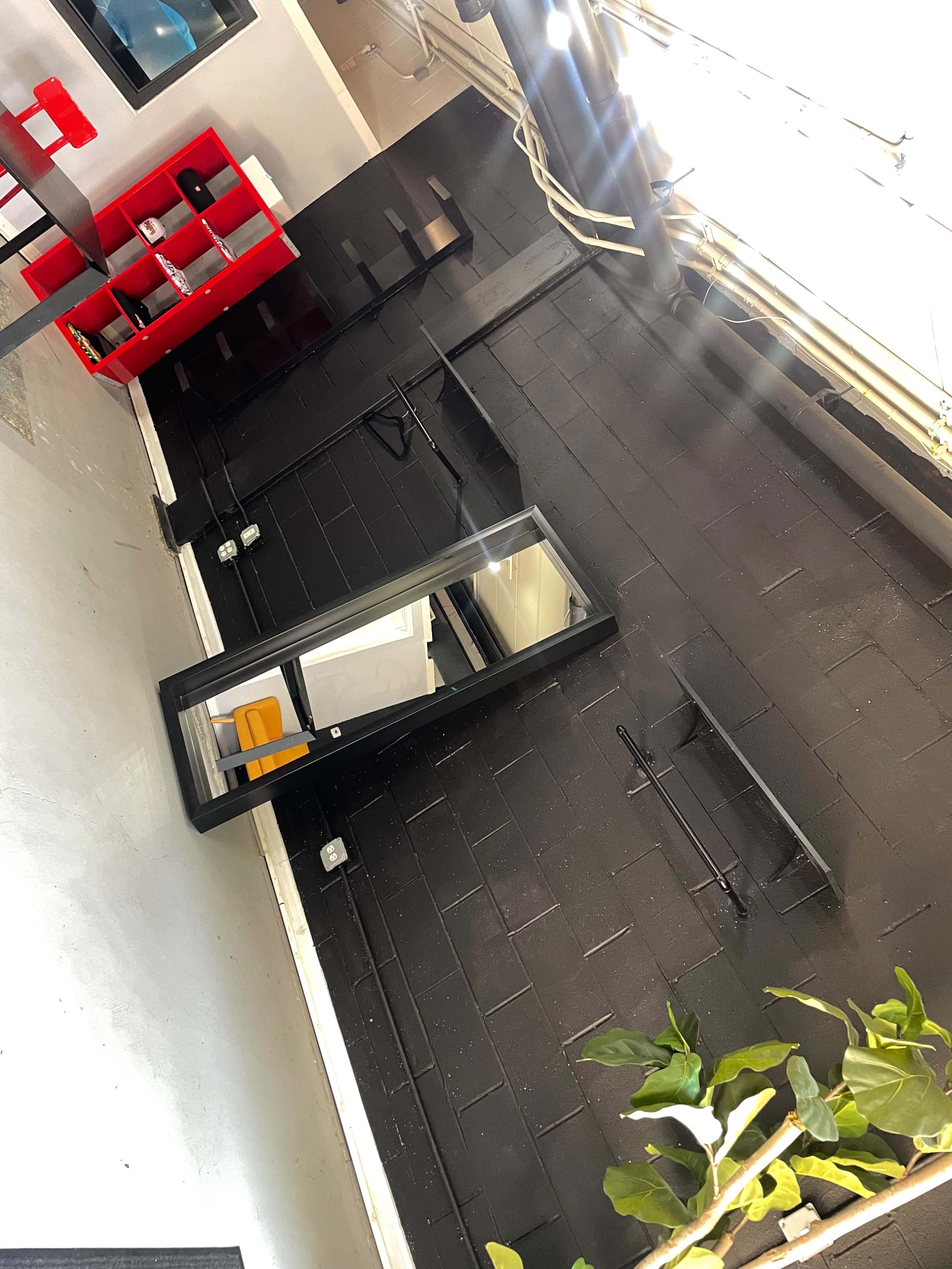 A modern interior space with a black wall, a large mirror, an orange chair, and red shelving units.
