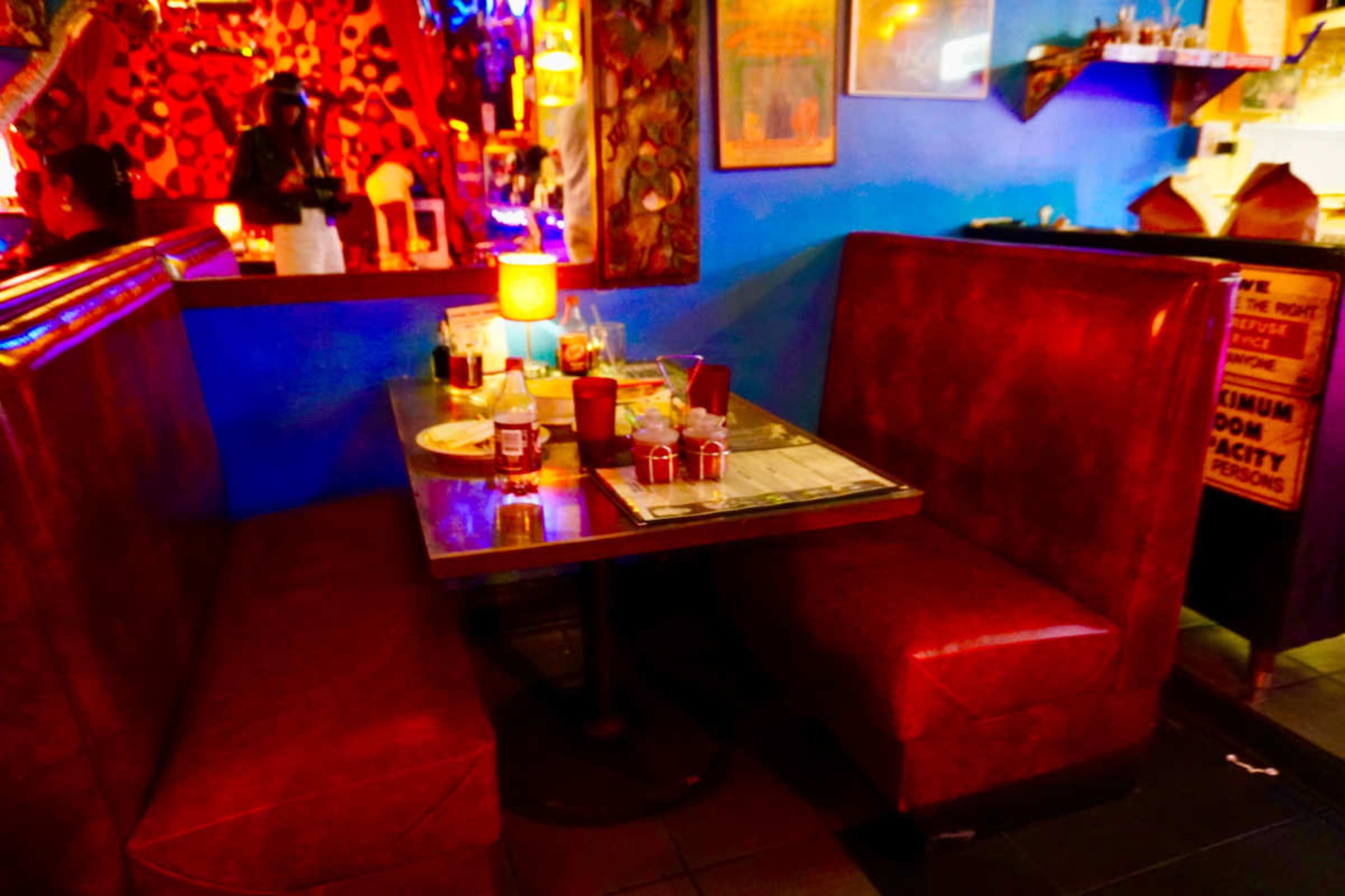 A booth table is set for dining in a brightly colored restaurant with vibrant decor and ambient lighting.