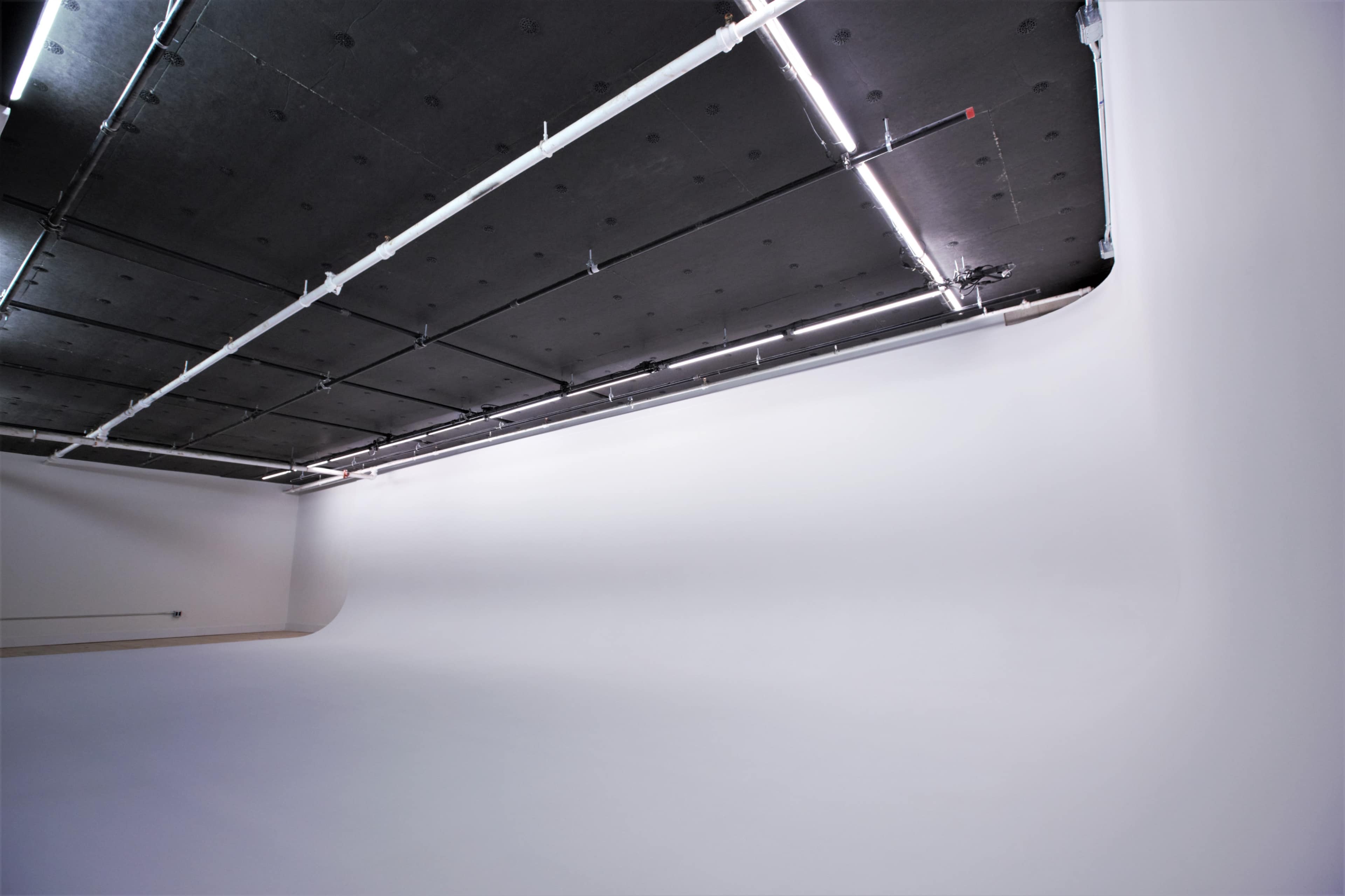 A large, empty studio space with a high ceiling and a white backdrop.