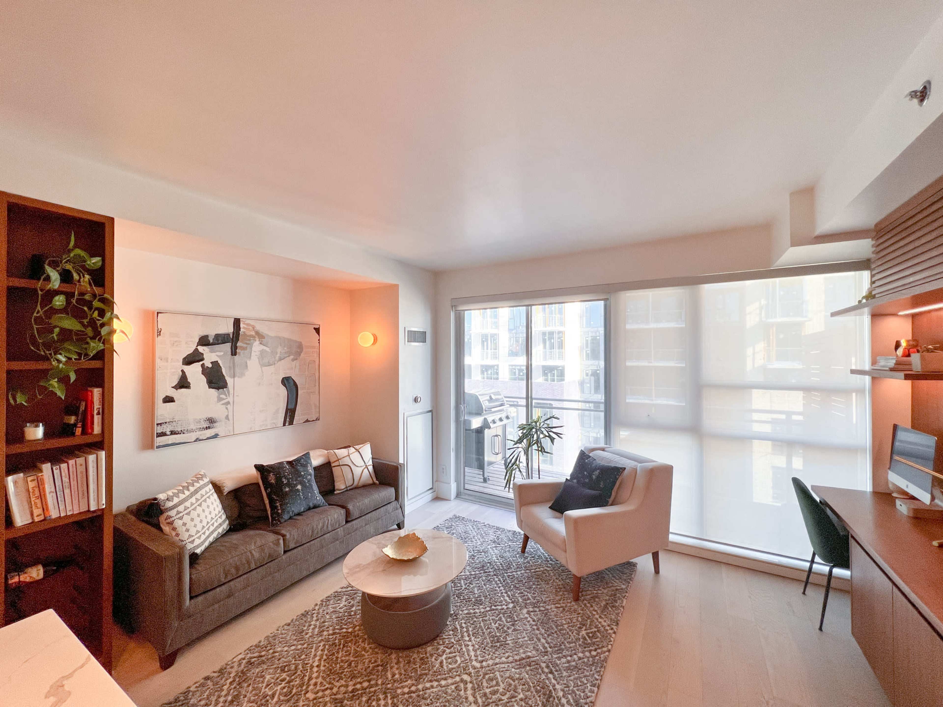 A modern living room with a brown sofa, a round coffee table, and large windows that let in natural light.