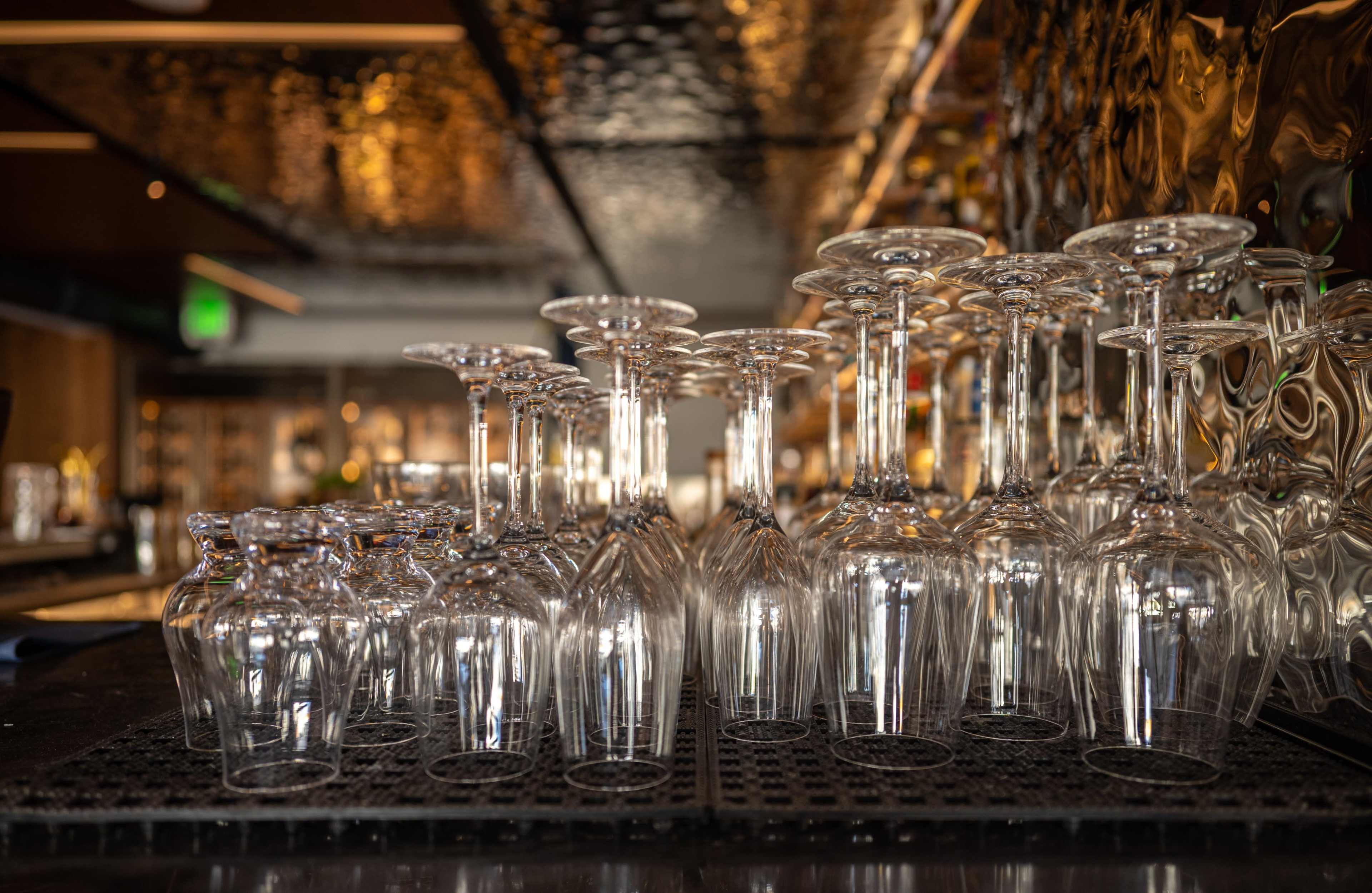 A row of clear wine glasses is stacked upside down on a bar countertop.