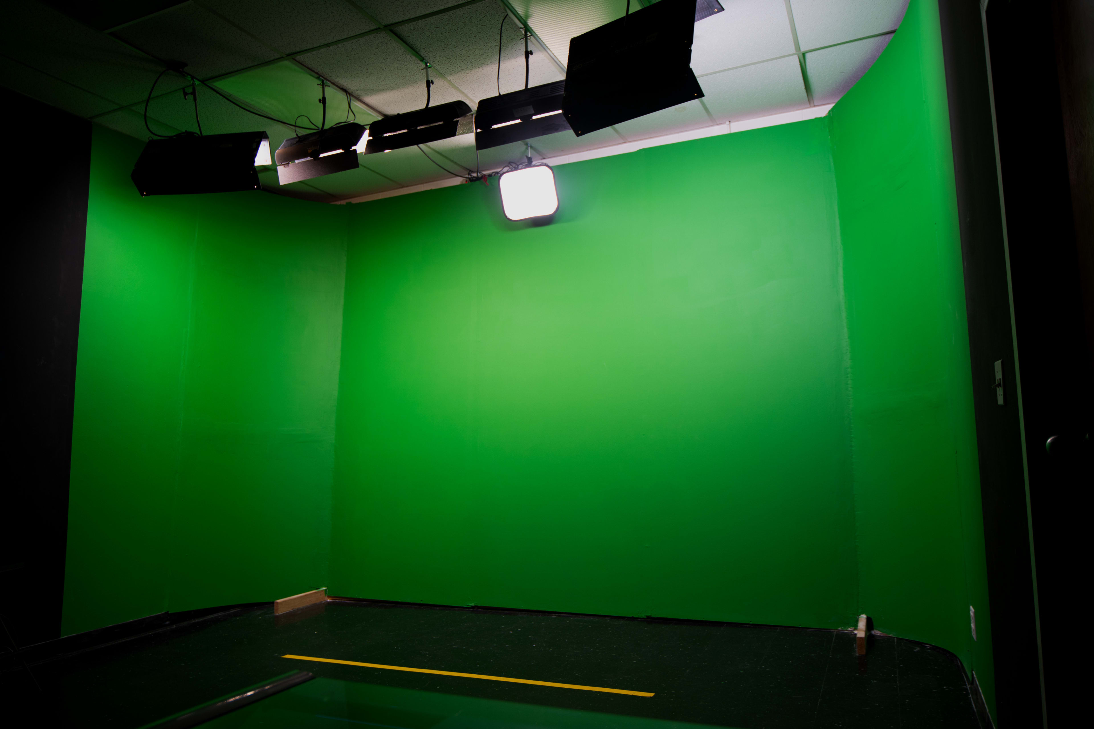 A green screen room with overhead lighting and a dark floor.