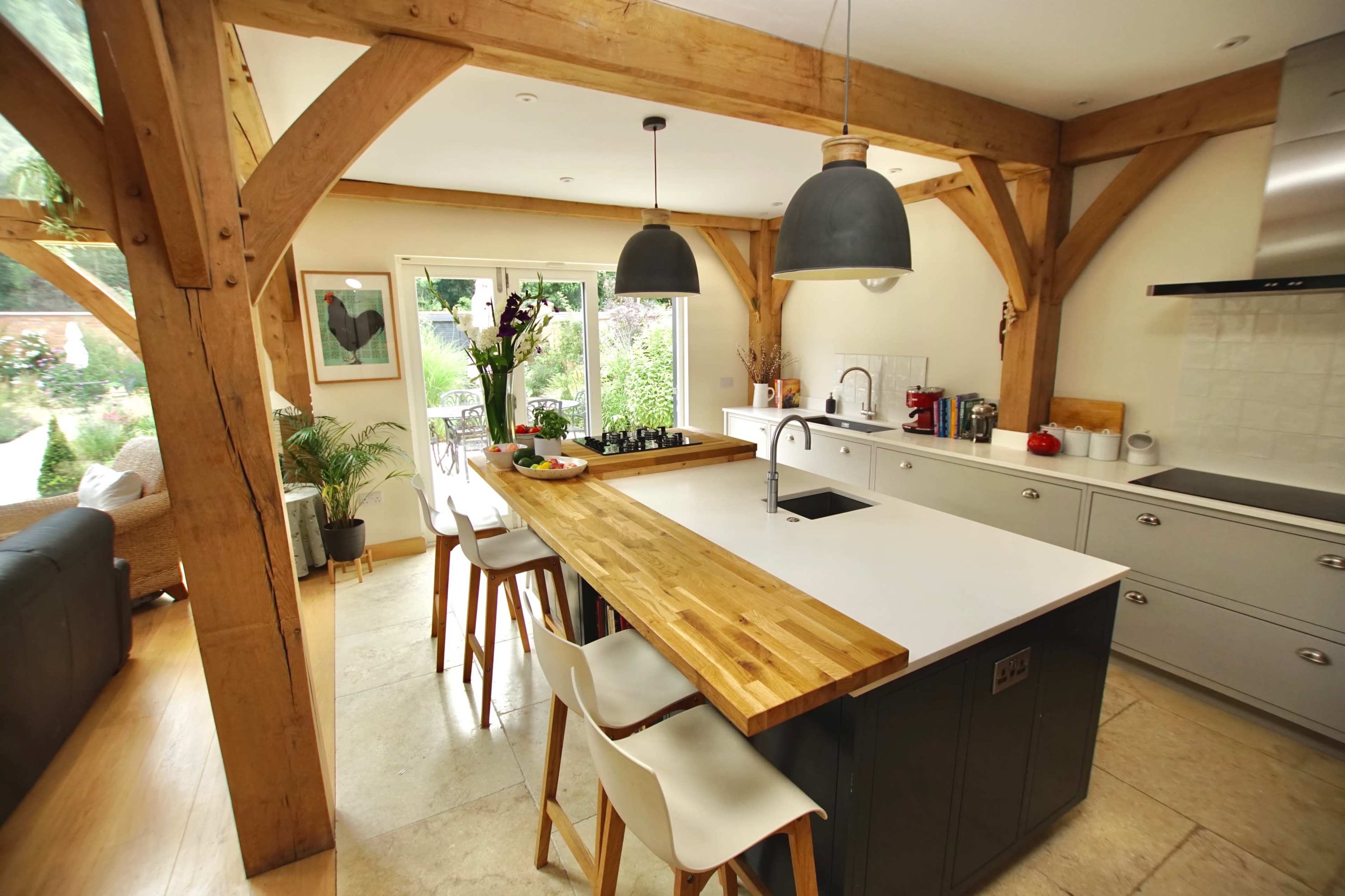 A modern kitchen with a central wooden island, gray cabinetry, and large pendant lights hanging above.